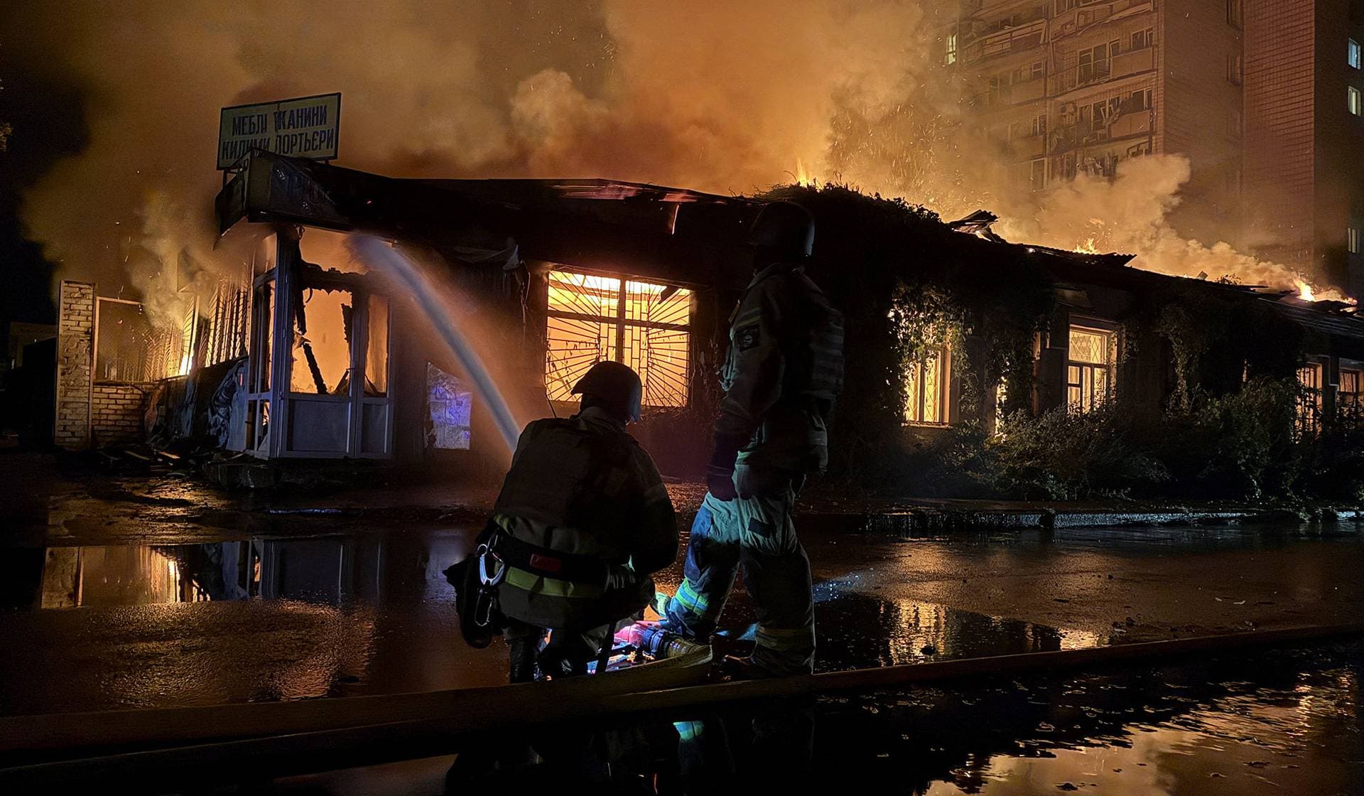 Firefighters work near a site of an apartment building hit by a Russian missile strike in Kyiv