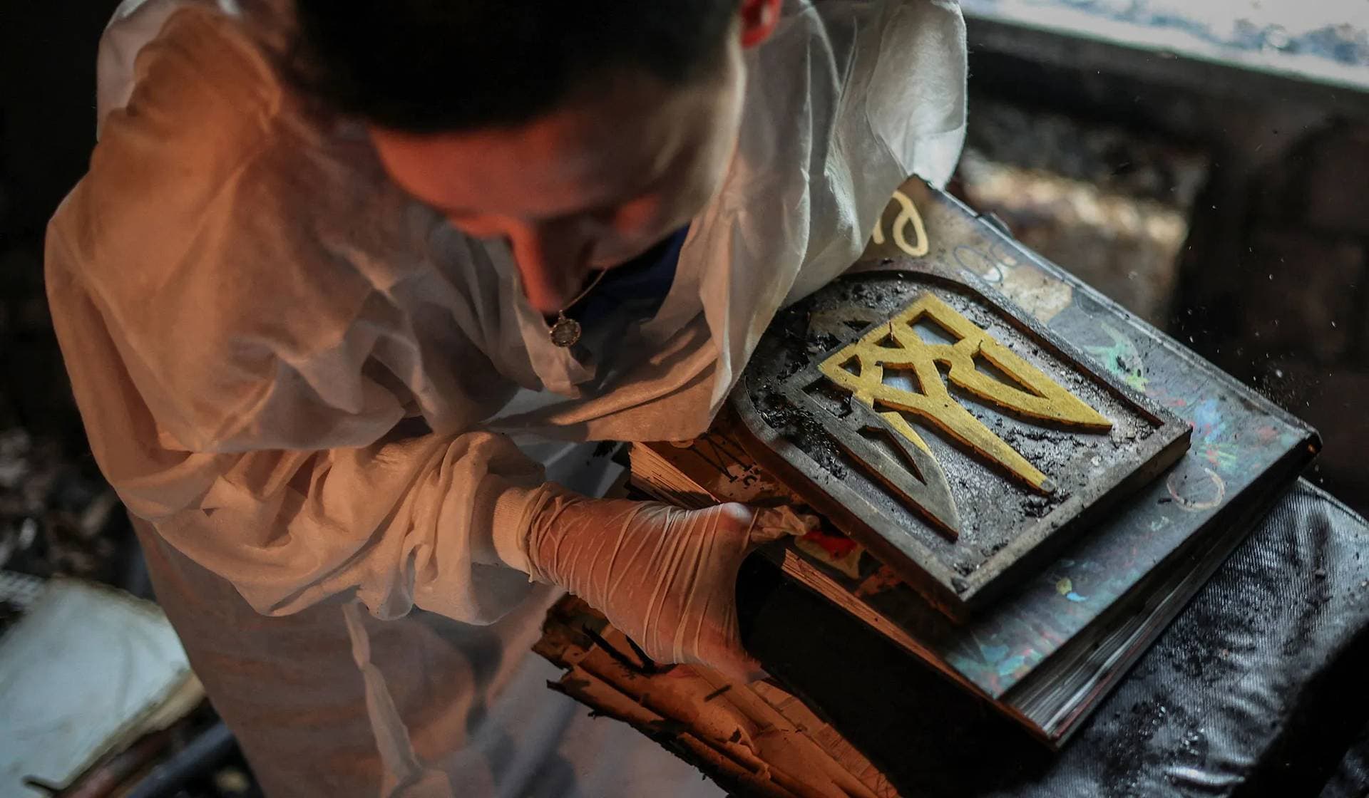 resident carries her remaining personal belongings and partially damaged Ukrainian coat of arms, the tryzub, carved out of wood by her father-in-law, in the burned down apartment, which was damaged during the strike in Kyiv