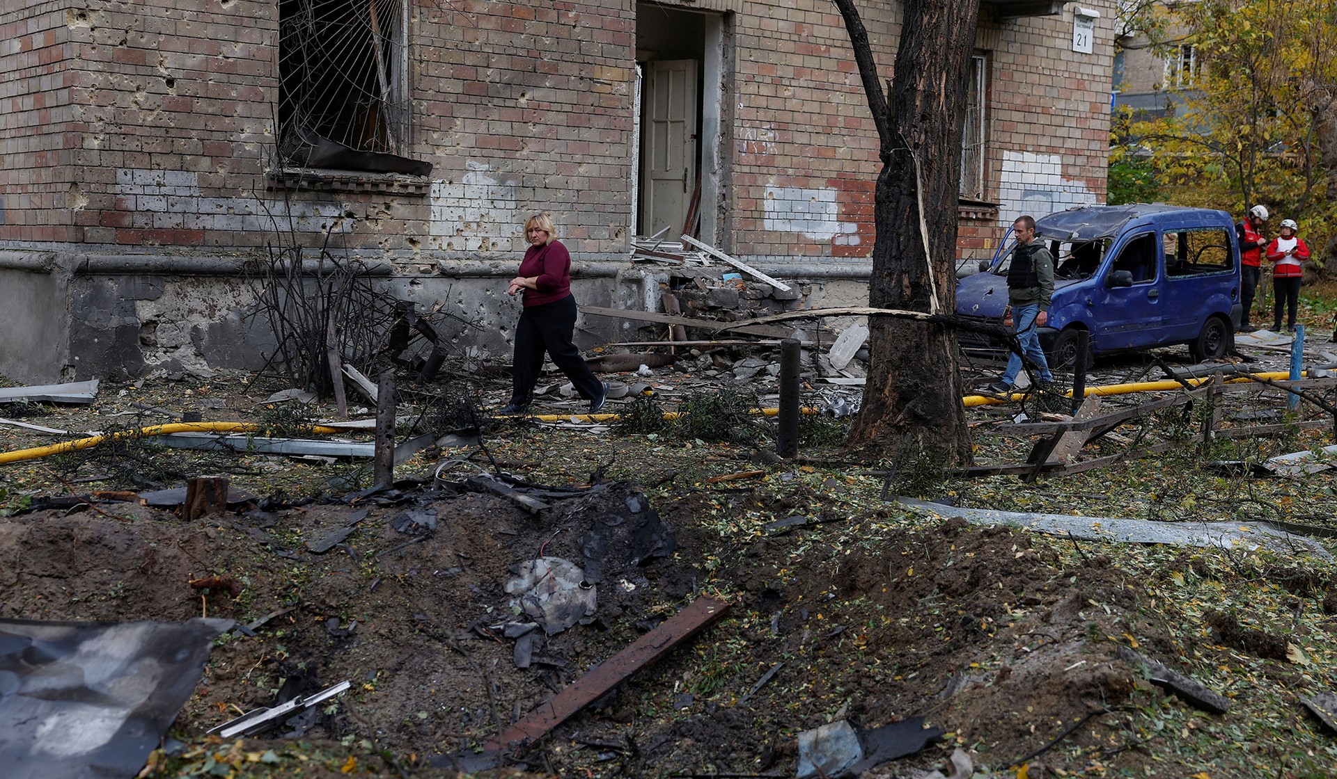 A woman walks past a crater that appeared at the site of a residential area after a Russian drone strike in Kyiv