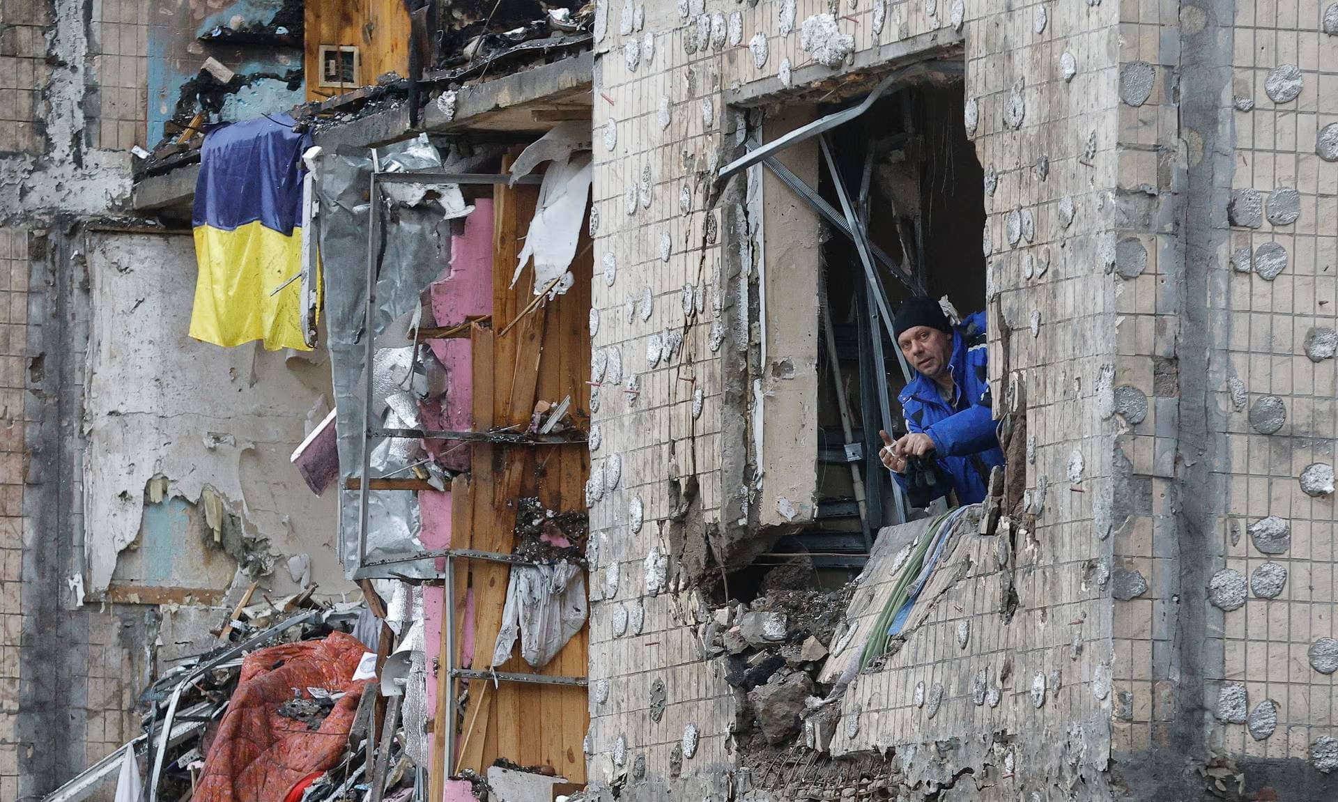 A man looks out the window of a destroyed flat of a residential building damaged by Russian shelling in Kyiv