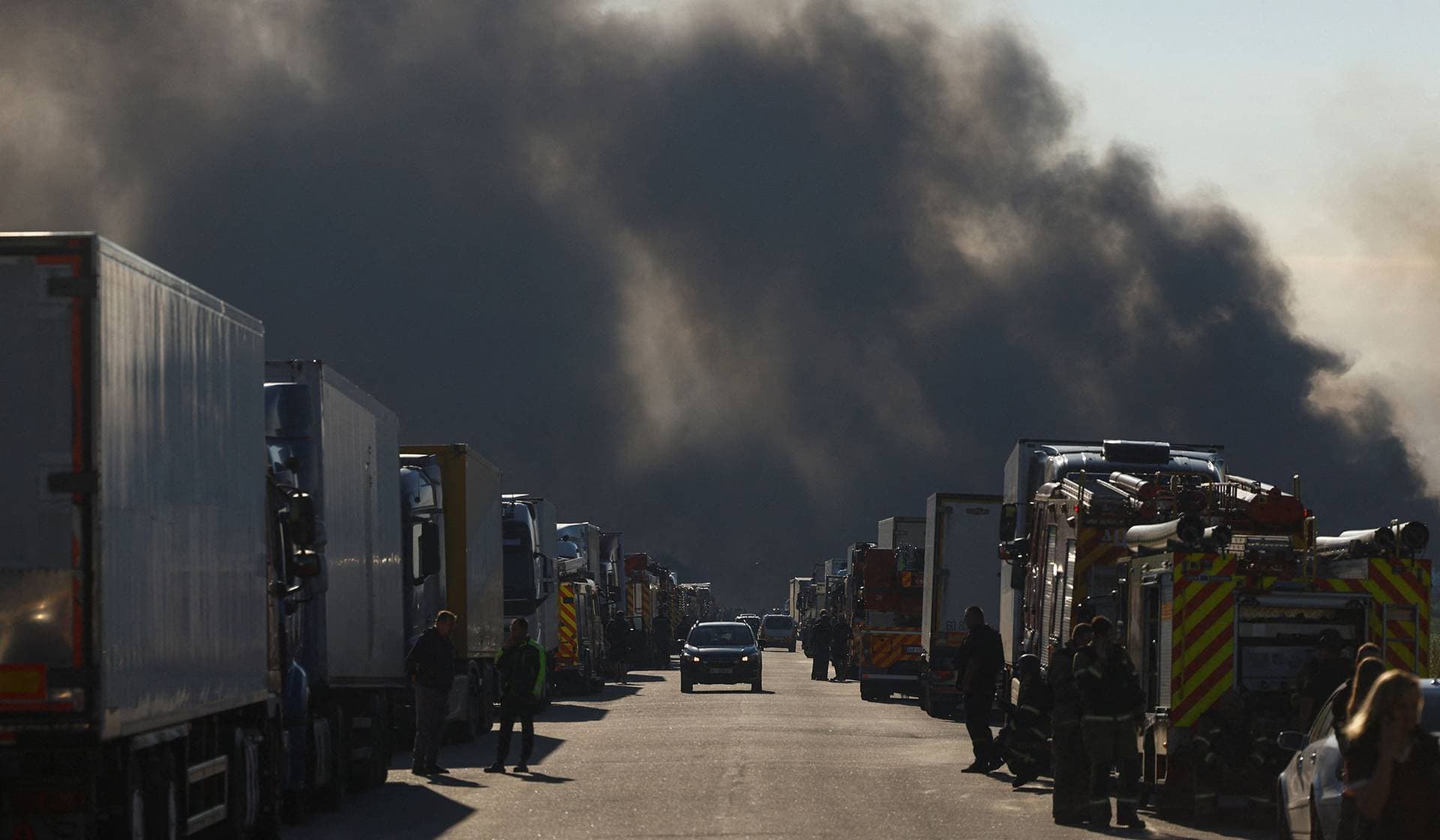 Firefighters and truck drivers gather at the site of a food warehouse fire after it was hit by a Russian missile strike in Kyiv Region