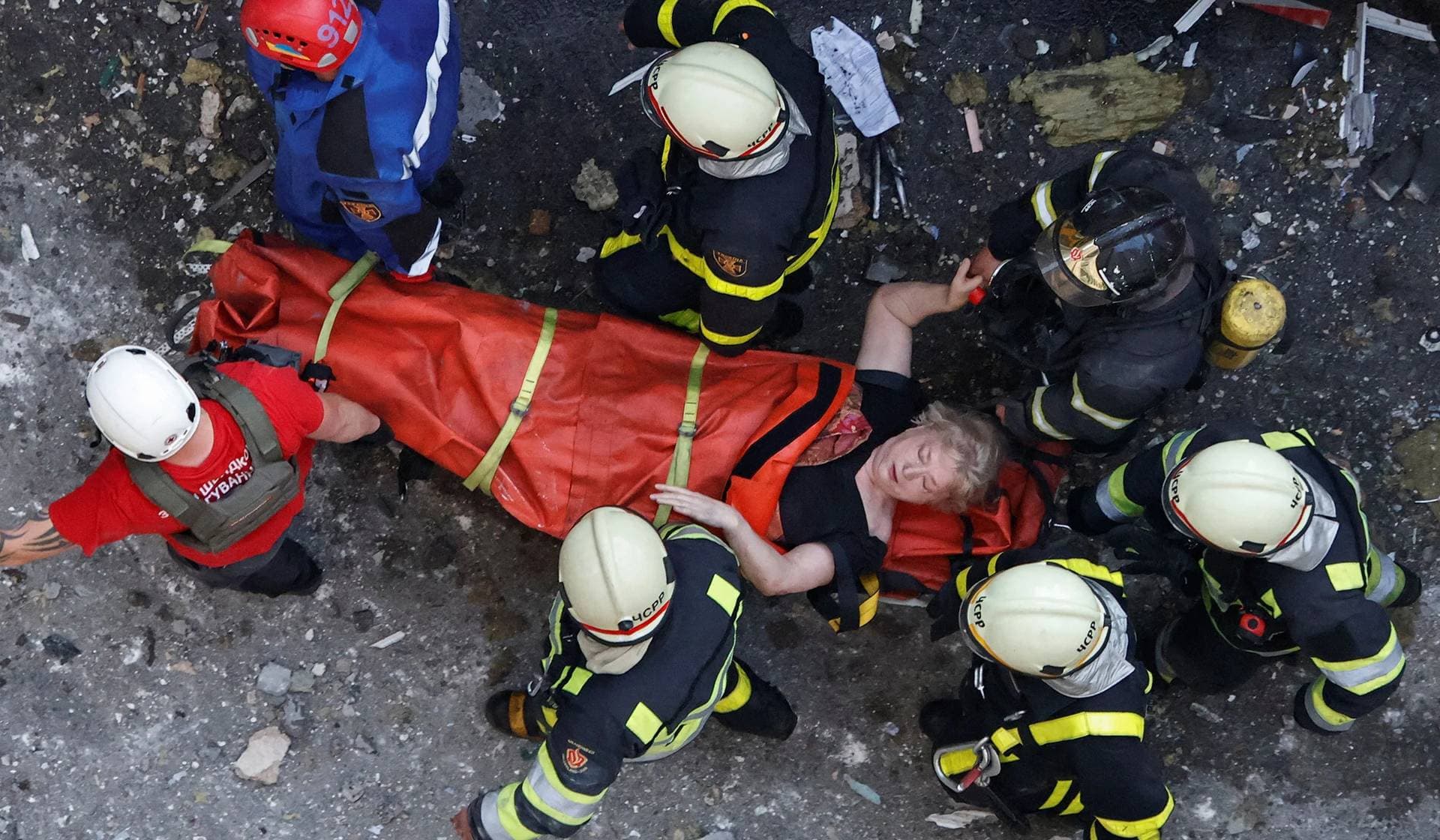 Rescuers carry a woman extricated from debris at the site of an apartment building damaged during Russian missile strikes in Kyiv