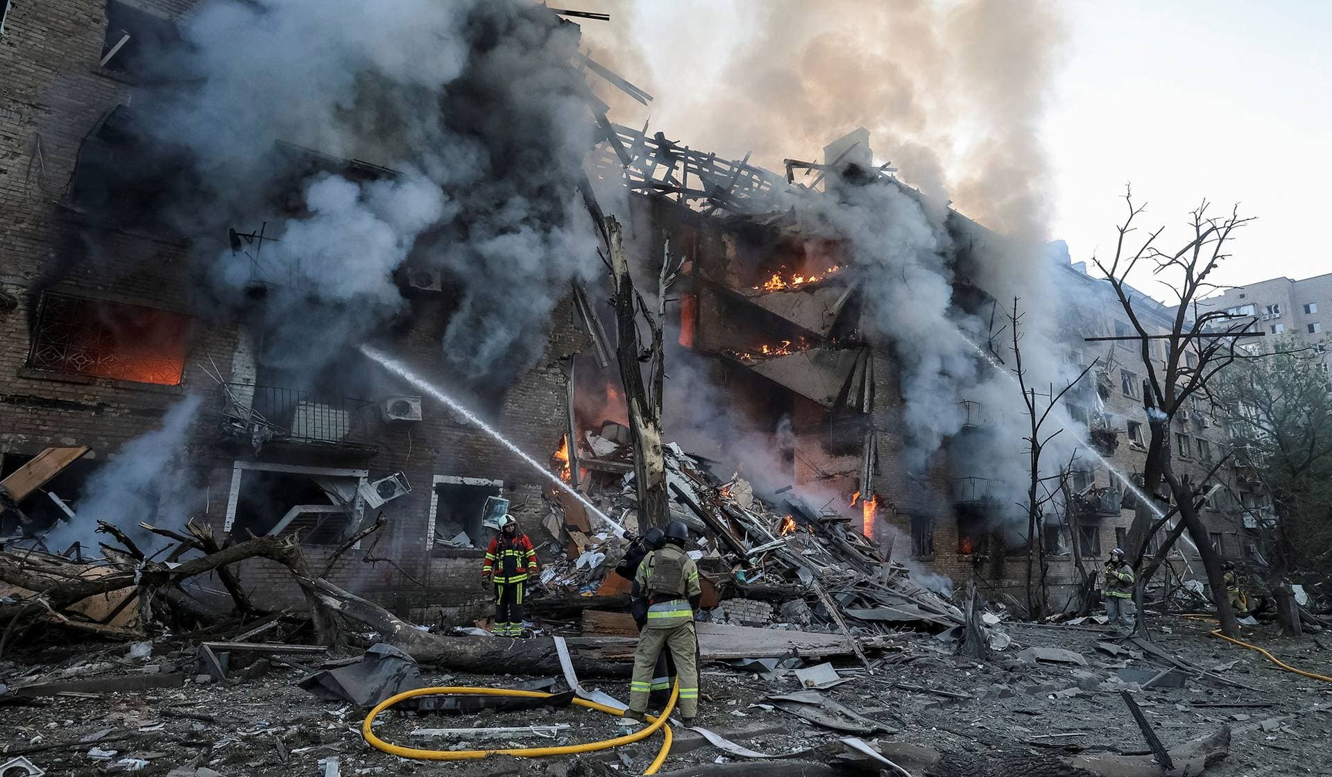 Firefighters work at the site of an apartment building destroyed by a Russian missile and drone strike in Kyiv
