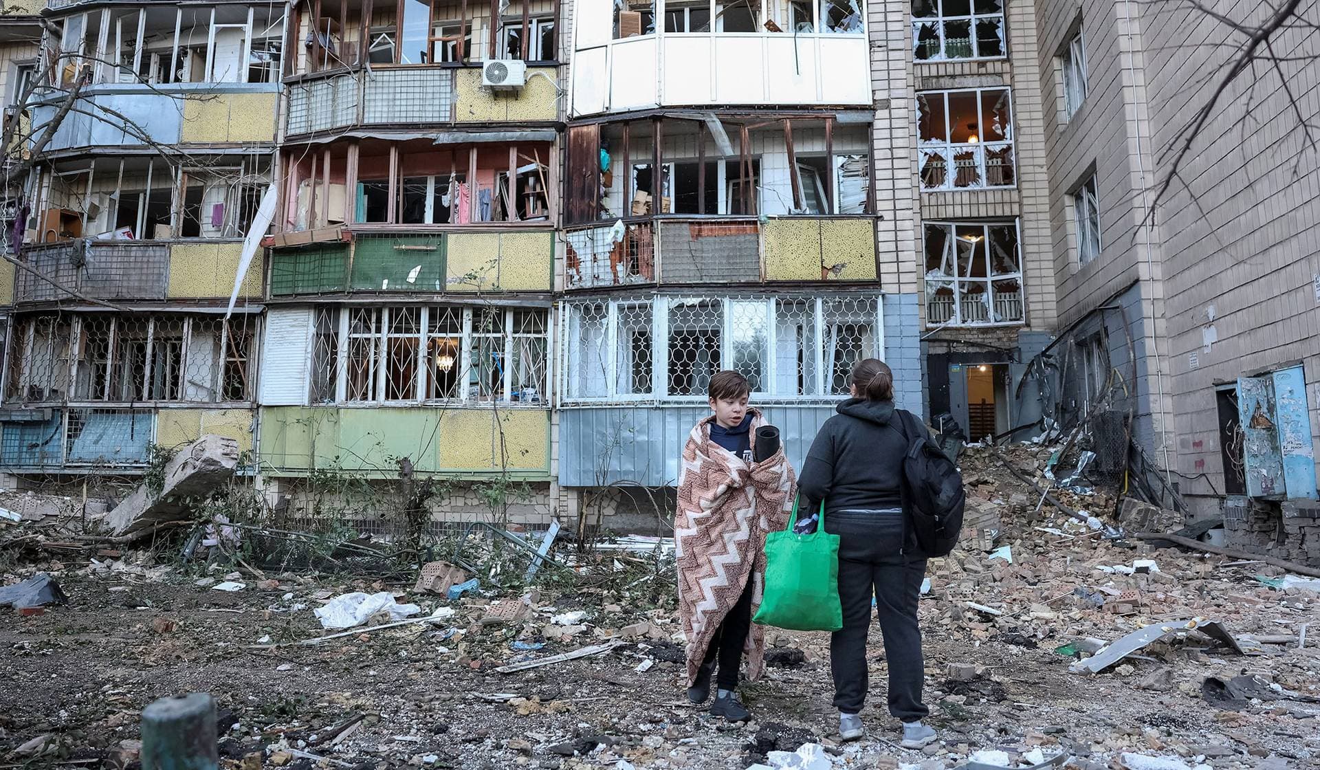 Residents stand at a site of an apartment building destroyed by a Russian missile strike in Kyiv