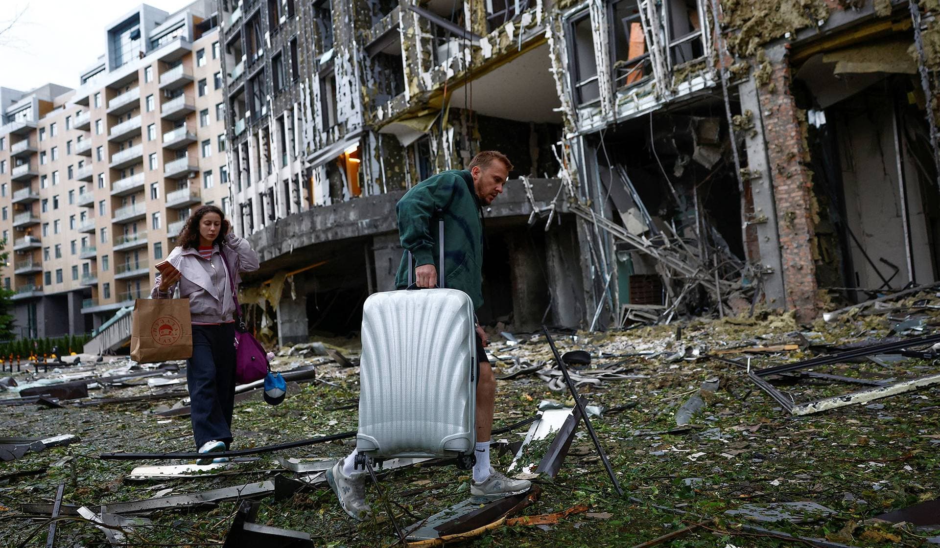 Residents carry their stuff in front of an apartment building, which was hit during Russian missile and drone strikes in Kyiv