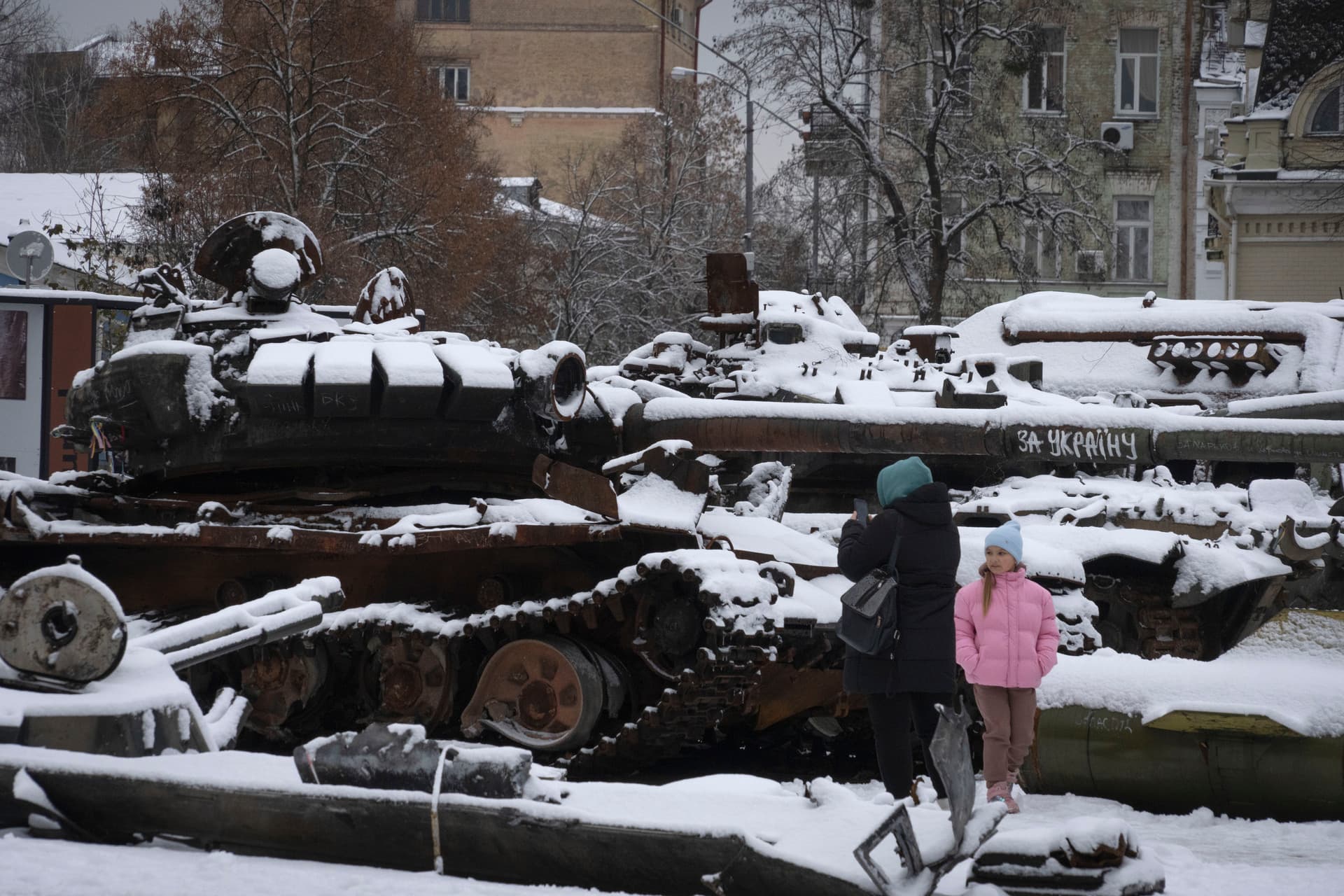 A woman and a child look at damaged Russian military vehicles in central Kyiv