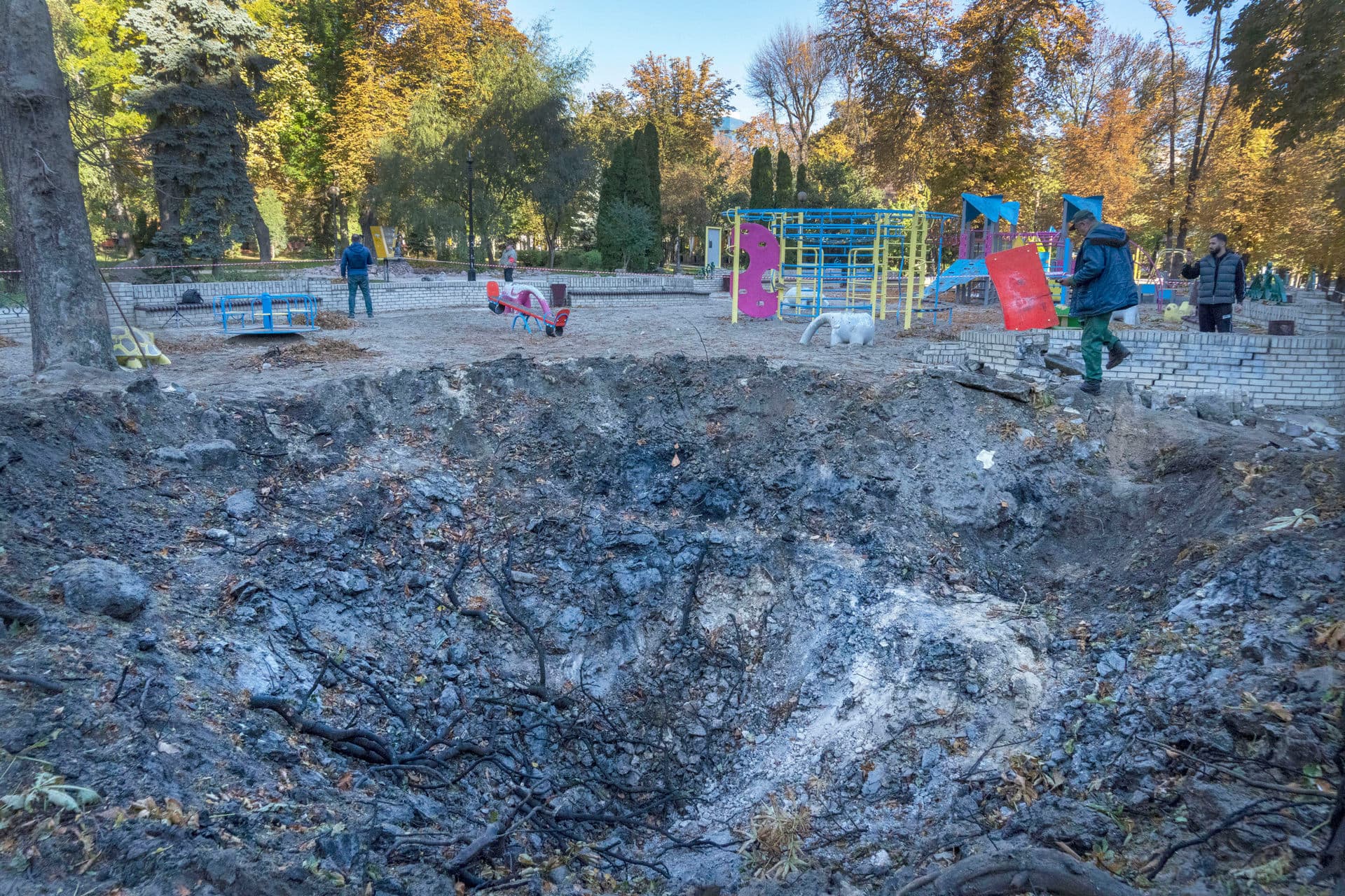 A man passes past a rocket crater at playground in city park in center Kyiv