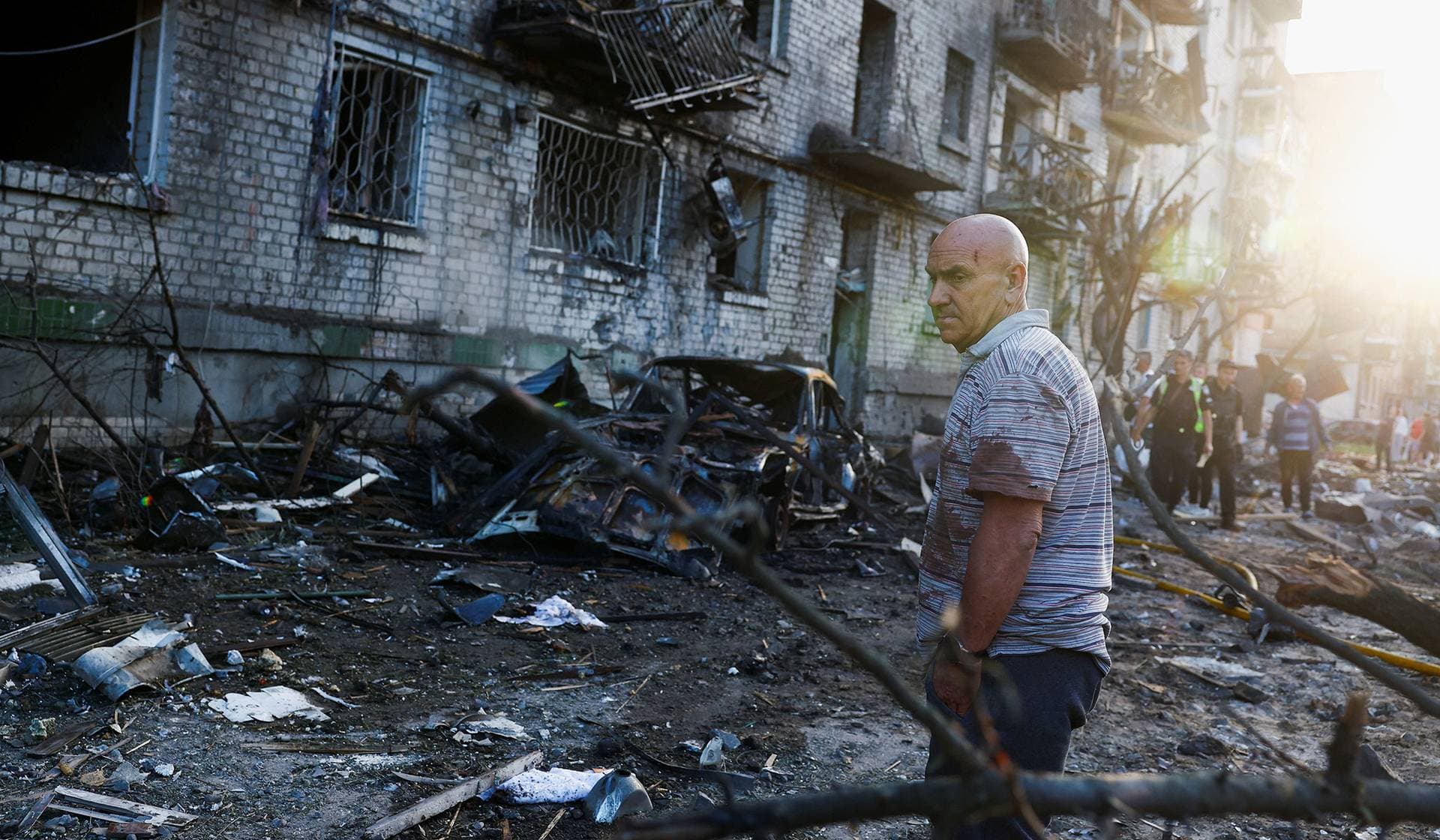 A man looks on at the site of an apartment building damaged during overnight Russian missile and drone strikes in Kyiv