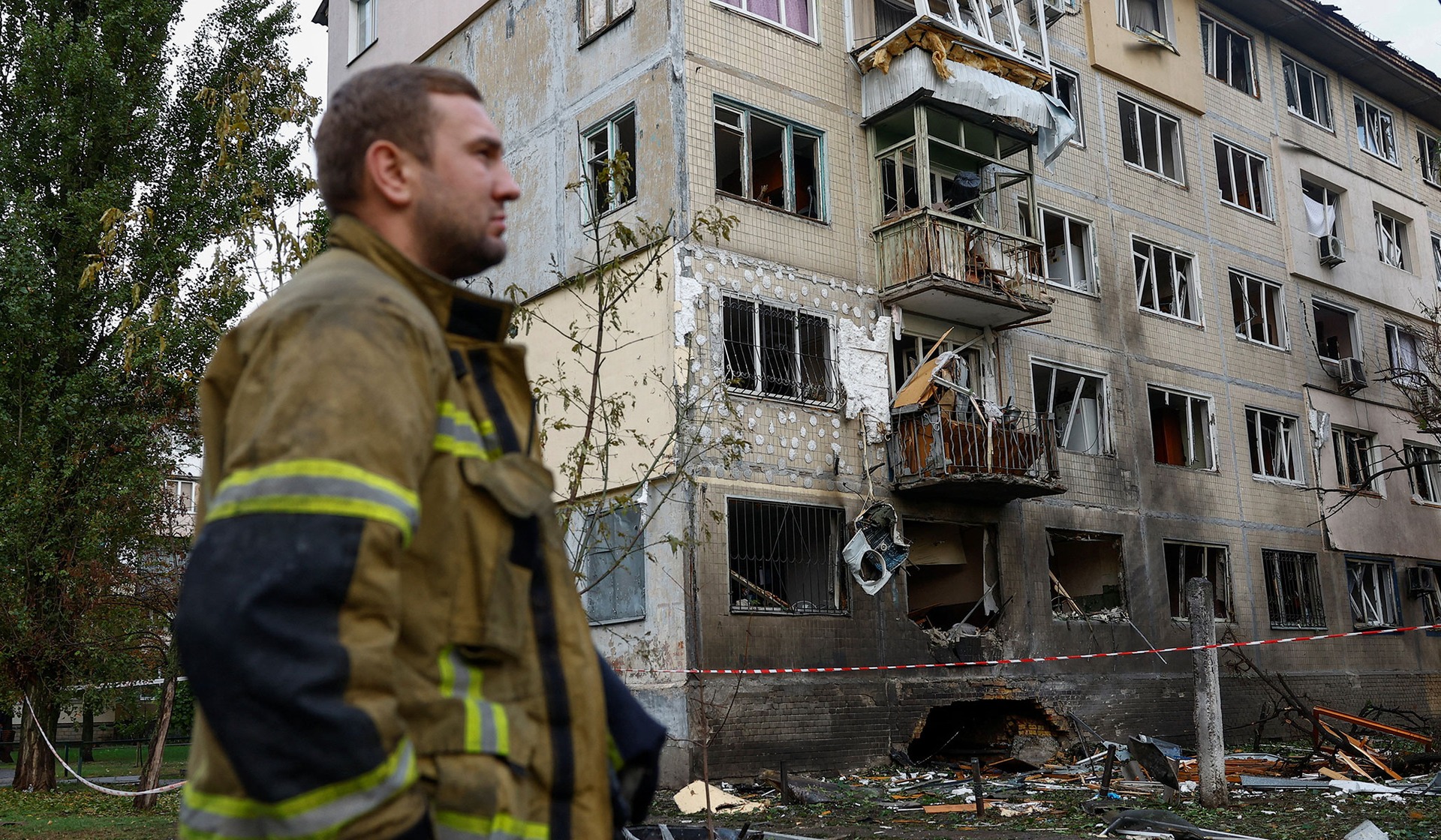 A rescuer stands in front of an apartment building which was hit by a Russian drone strike in Kyiv