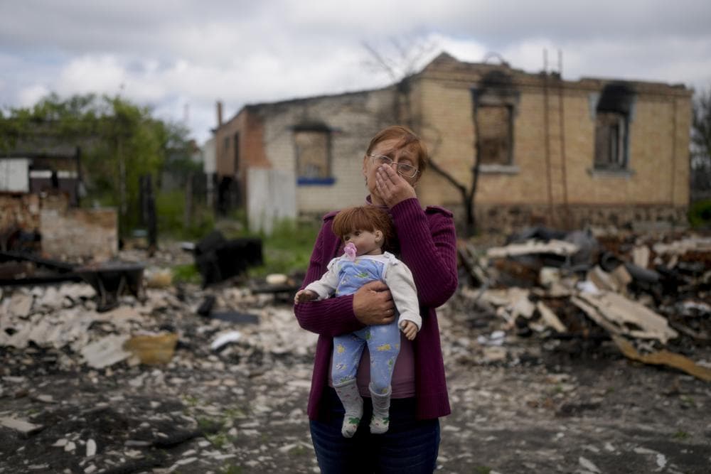 Nila Zelinska holds a doll belonging to her granddaughter, she was able to find in her destroyed house in Potashnya