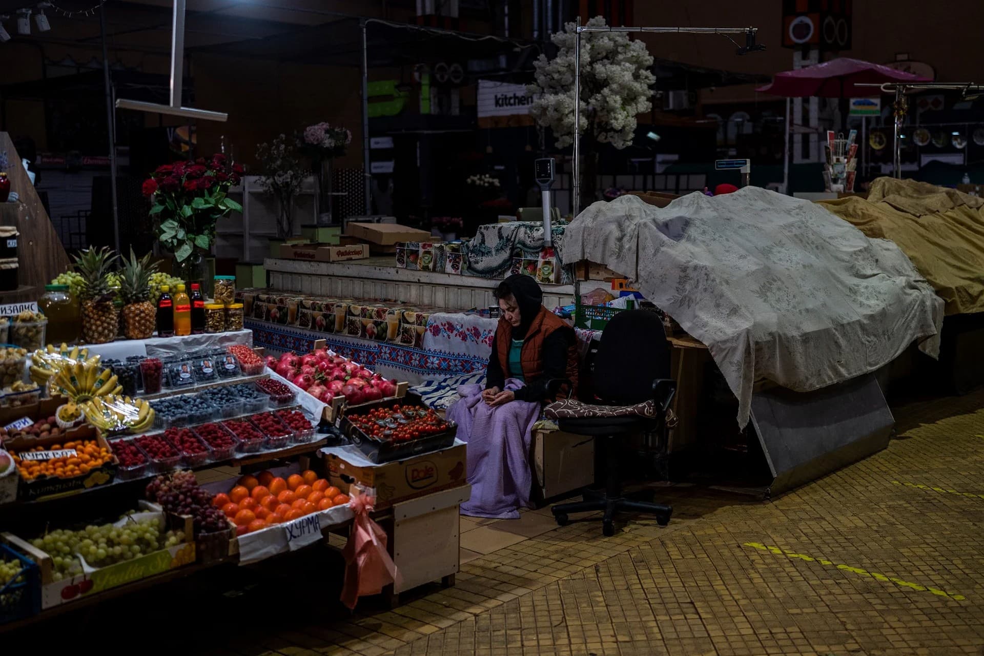 A fruit vendor waits for customers inside a market in Kyiv