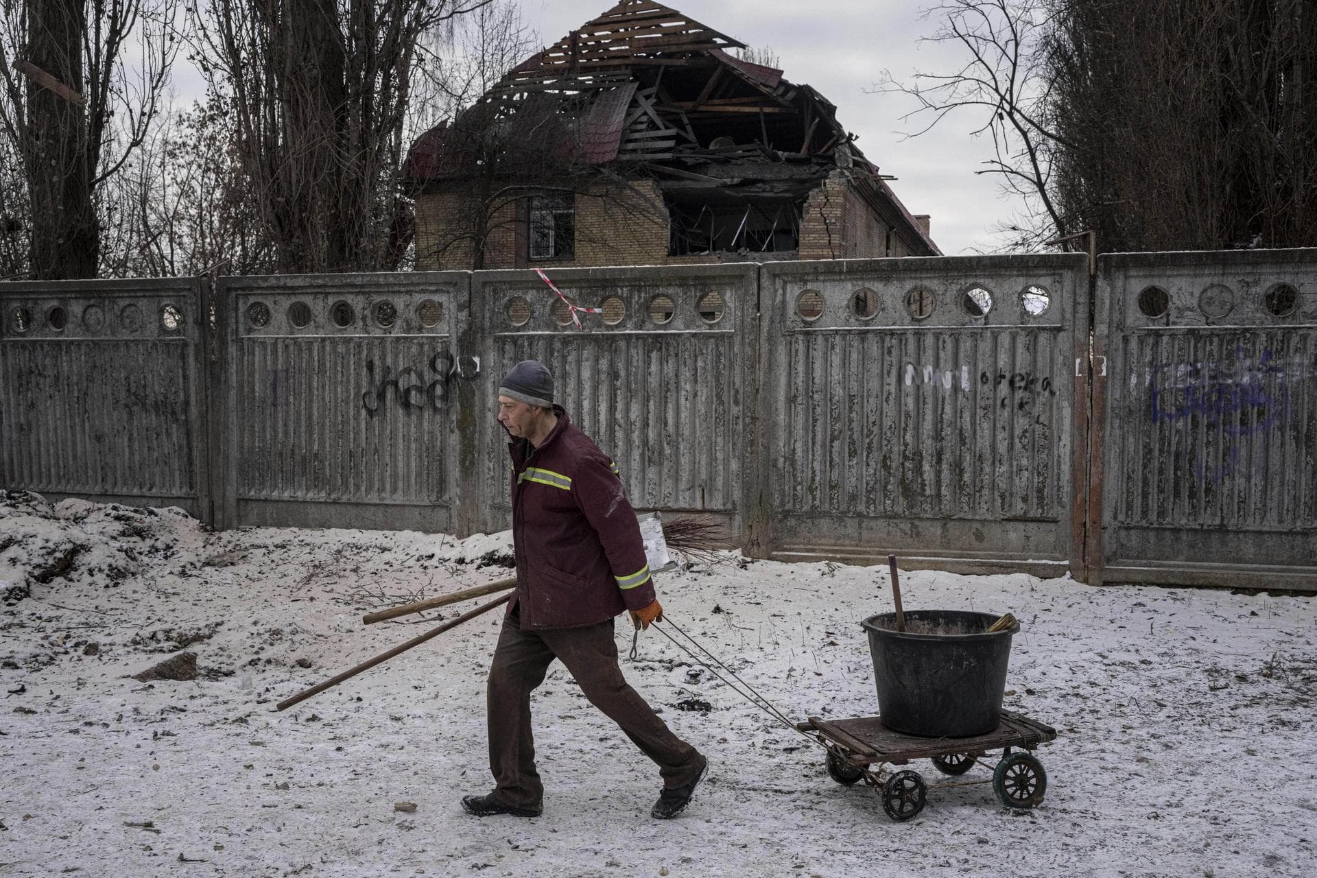 A municipal worker walks in front of a tax office building that have been heavily damaged by a Russian attack in Kyiv