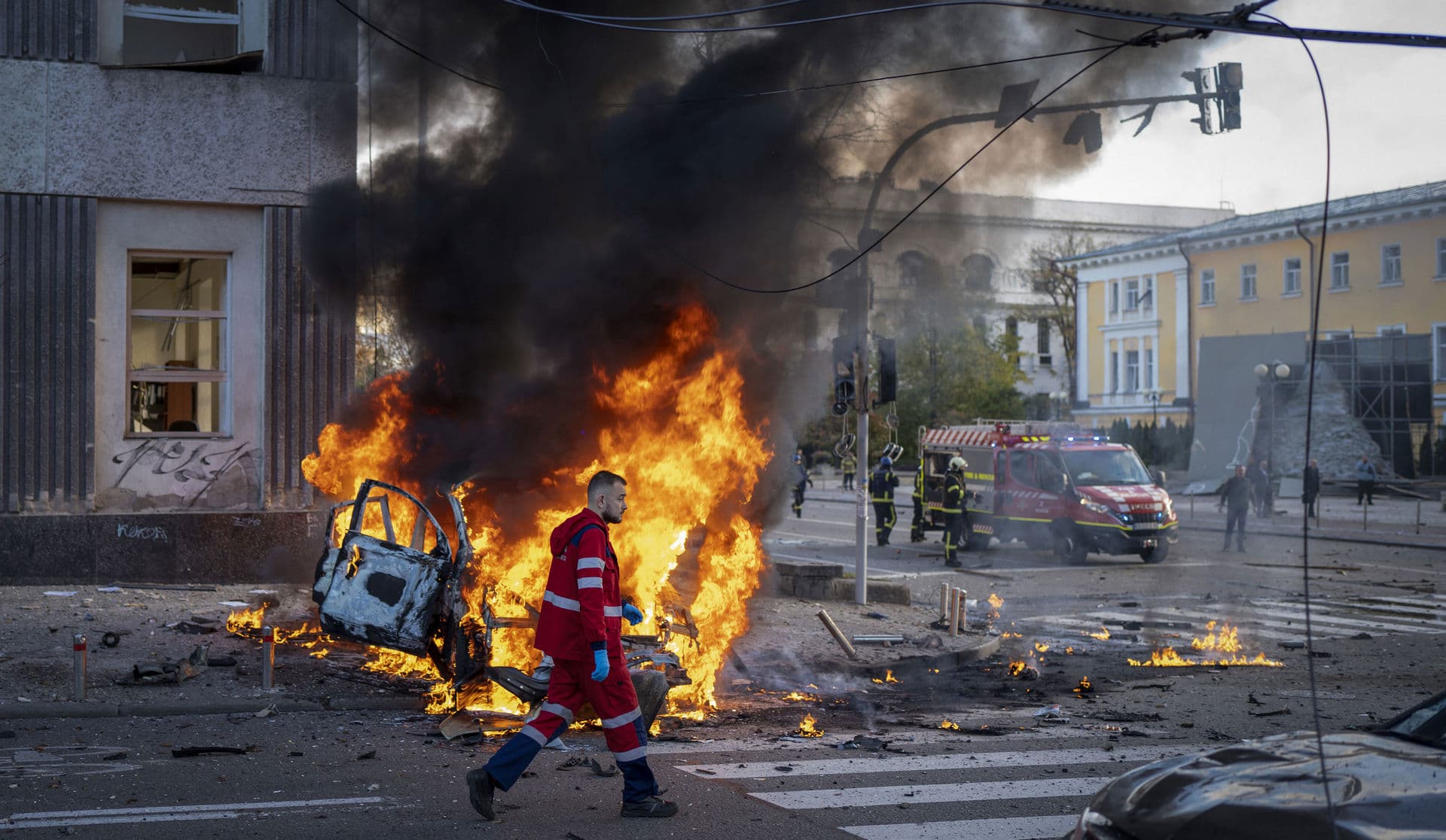 A medical worker runs past a burning car after a Russian attack in Kyiv