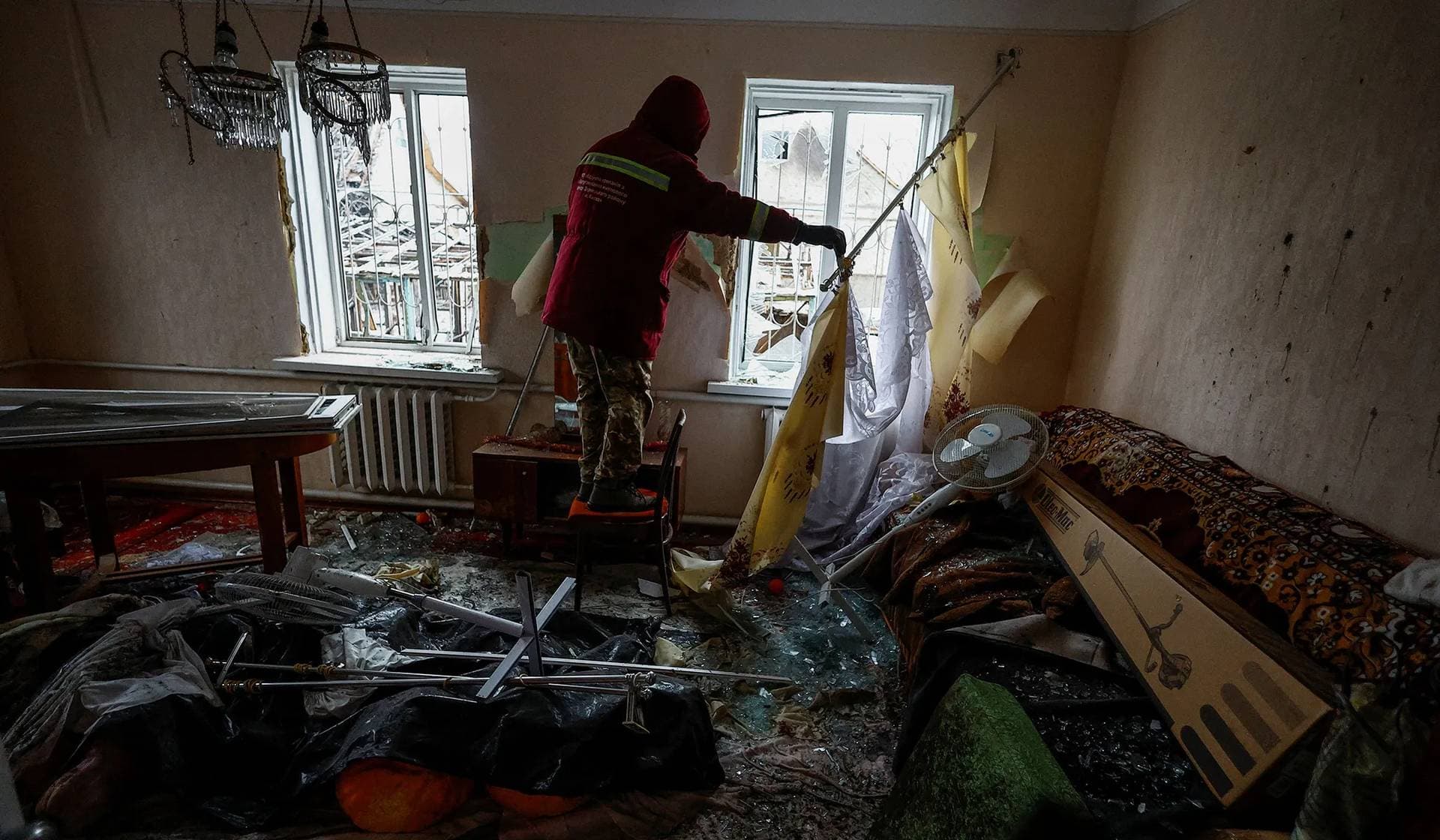 A municipal worker removes debris at a site of a Russian missile strike in Kyiv