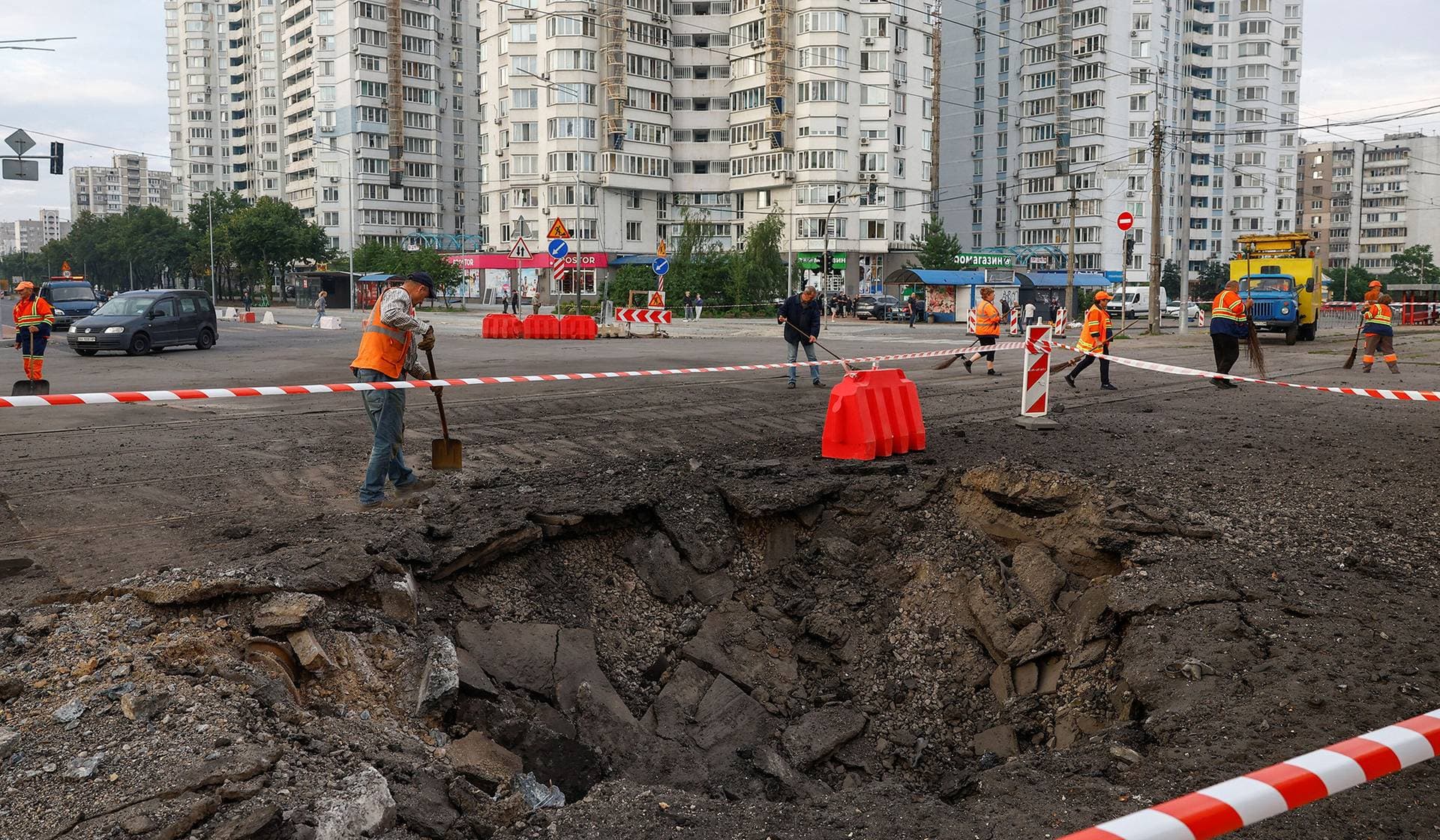 Municipal employees remove debris next to a crater after Russian missile strikes in Kyiv