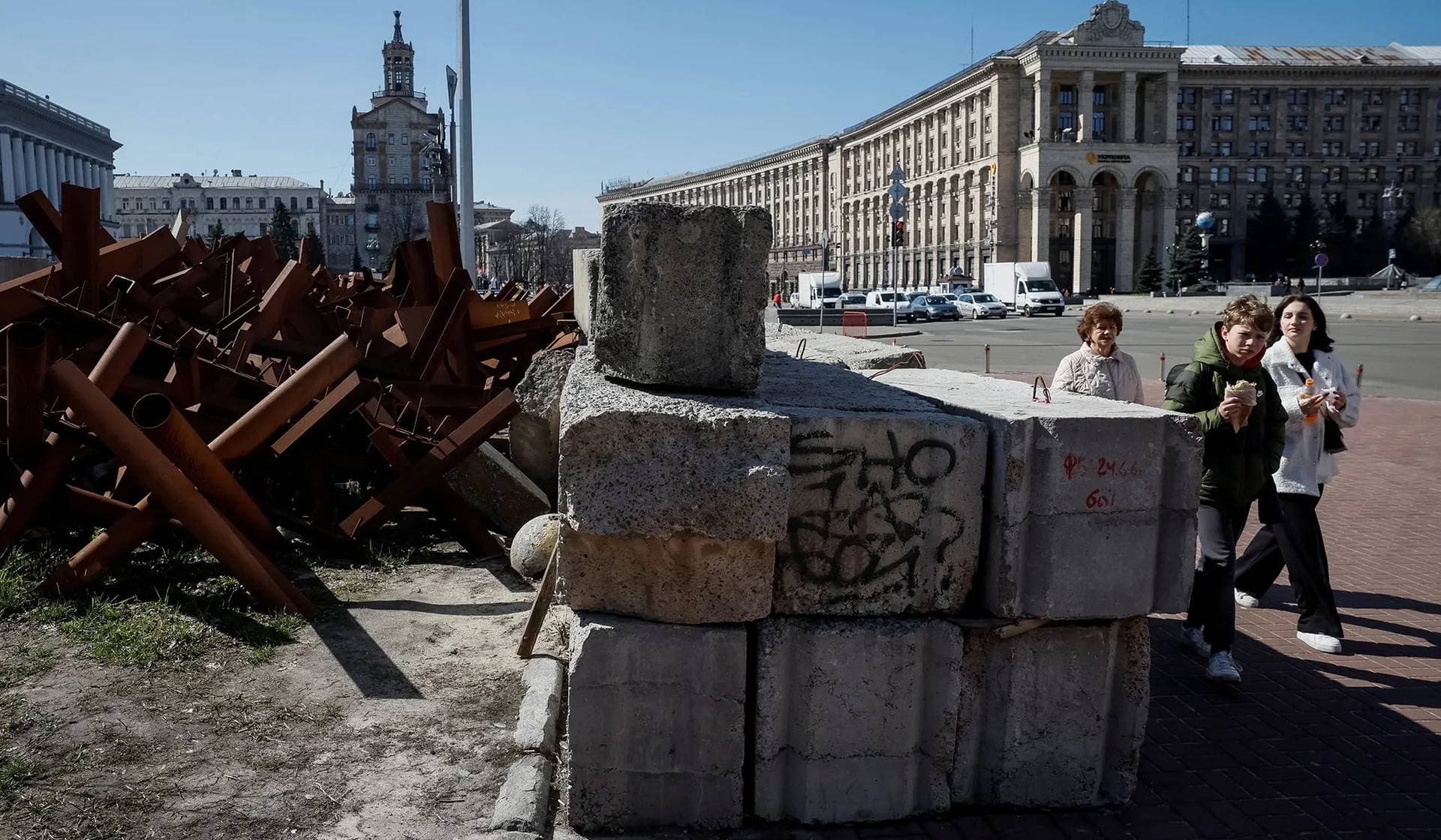 People walk down a street near anti-tank constructions in central Kyiv