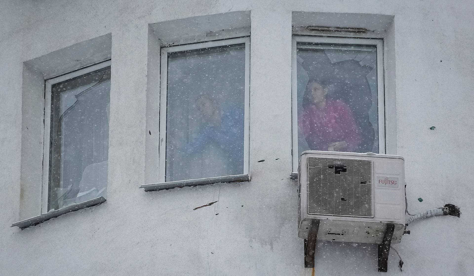 Residents fix broken windows with tape in an apartment building damaged by a Russian drone strike in Kyiv