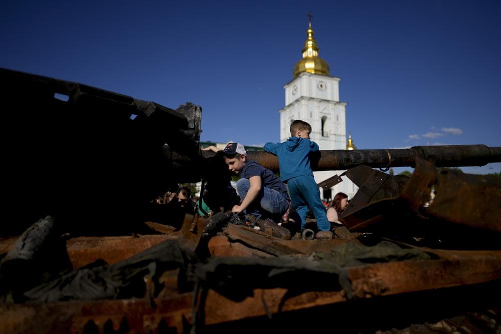 Children play on a destroyed Russian tank placed as a symbol of war during Kyiv Day celebrations in downtown Kyiv