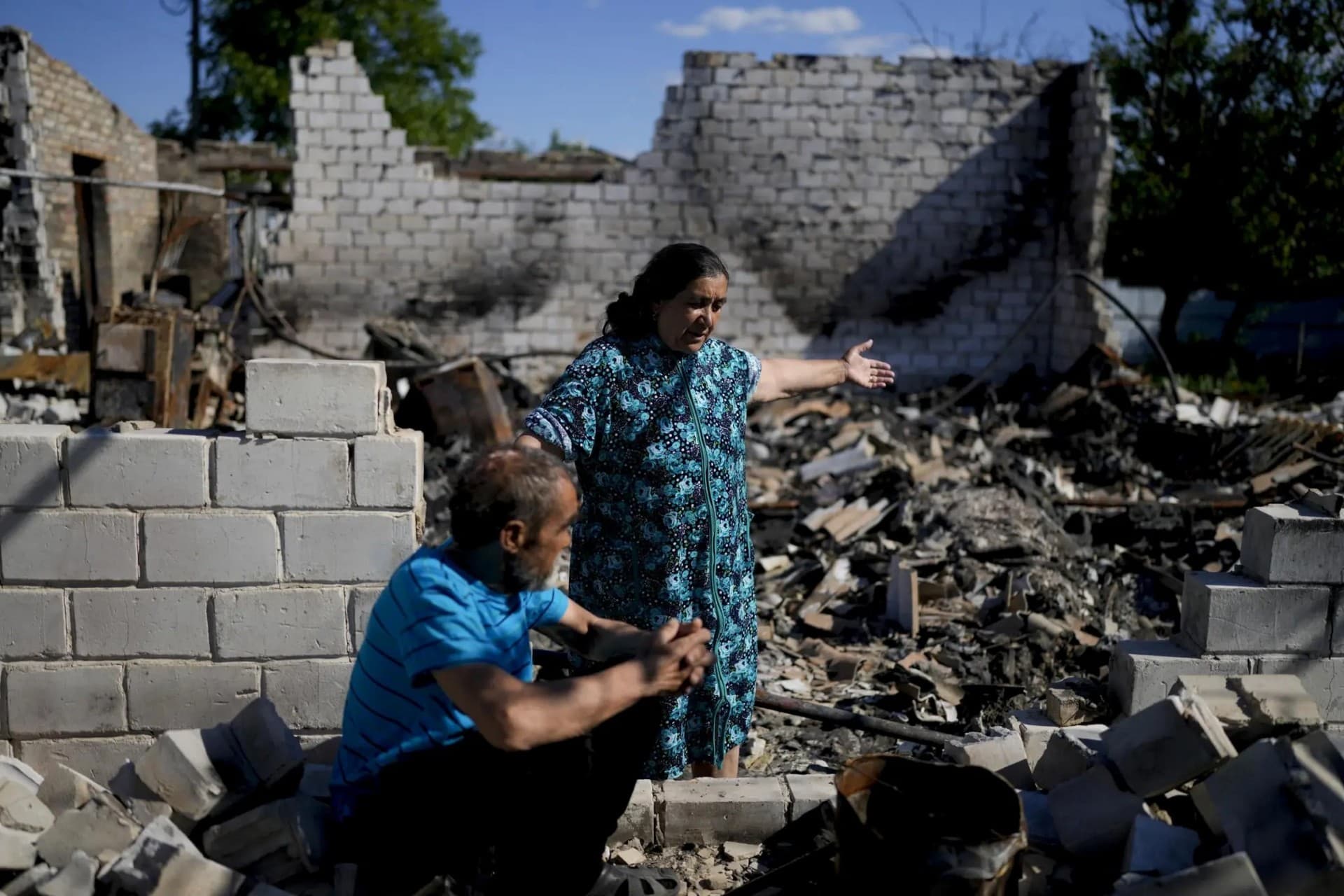 Nastasia Vladimirovna shows part of her house destroyed by attacks beside her husband in Mostyshche