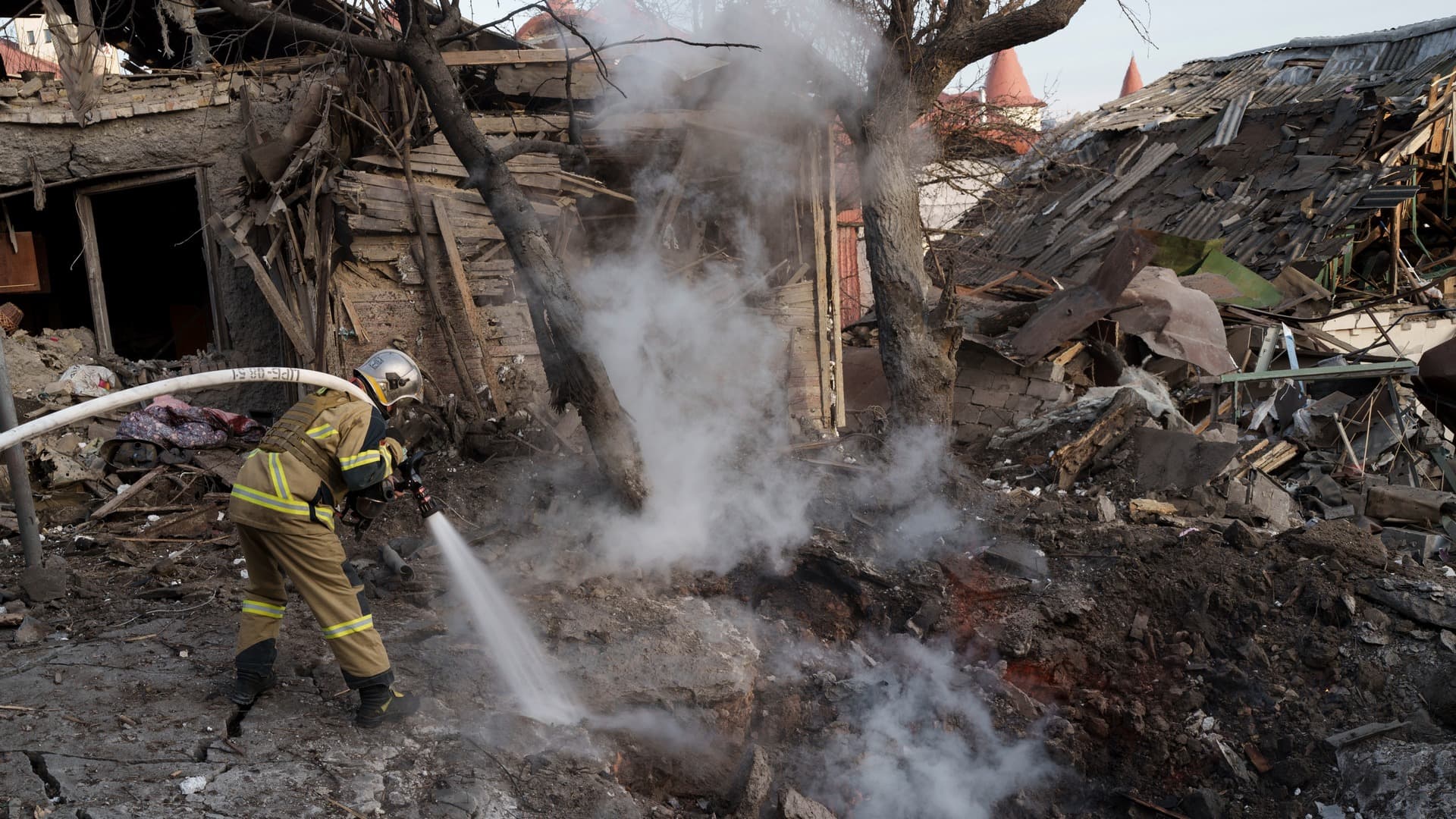 Firefighters extinguish a fire next to houses destroyed during a Russian attack in Kyiv