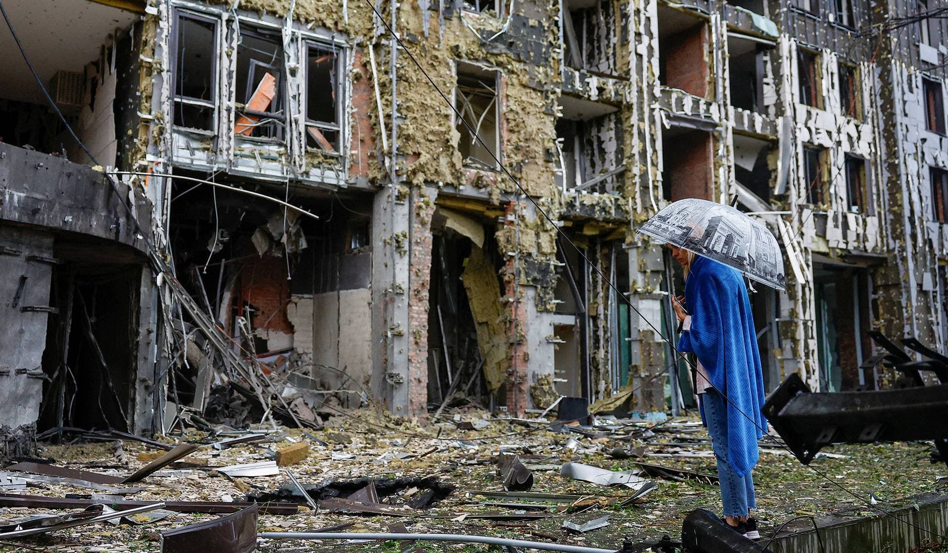 A resident stands in front of an apartment building, which was hit during Russian missile and drone strikes in Kyiv
