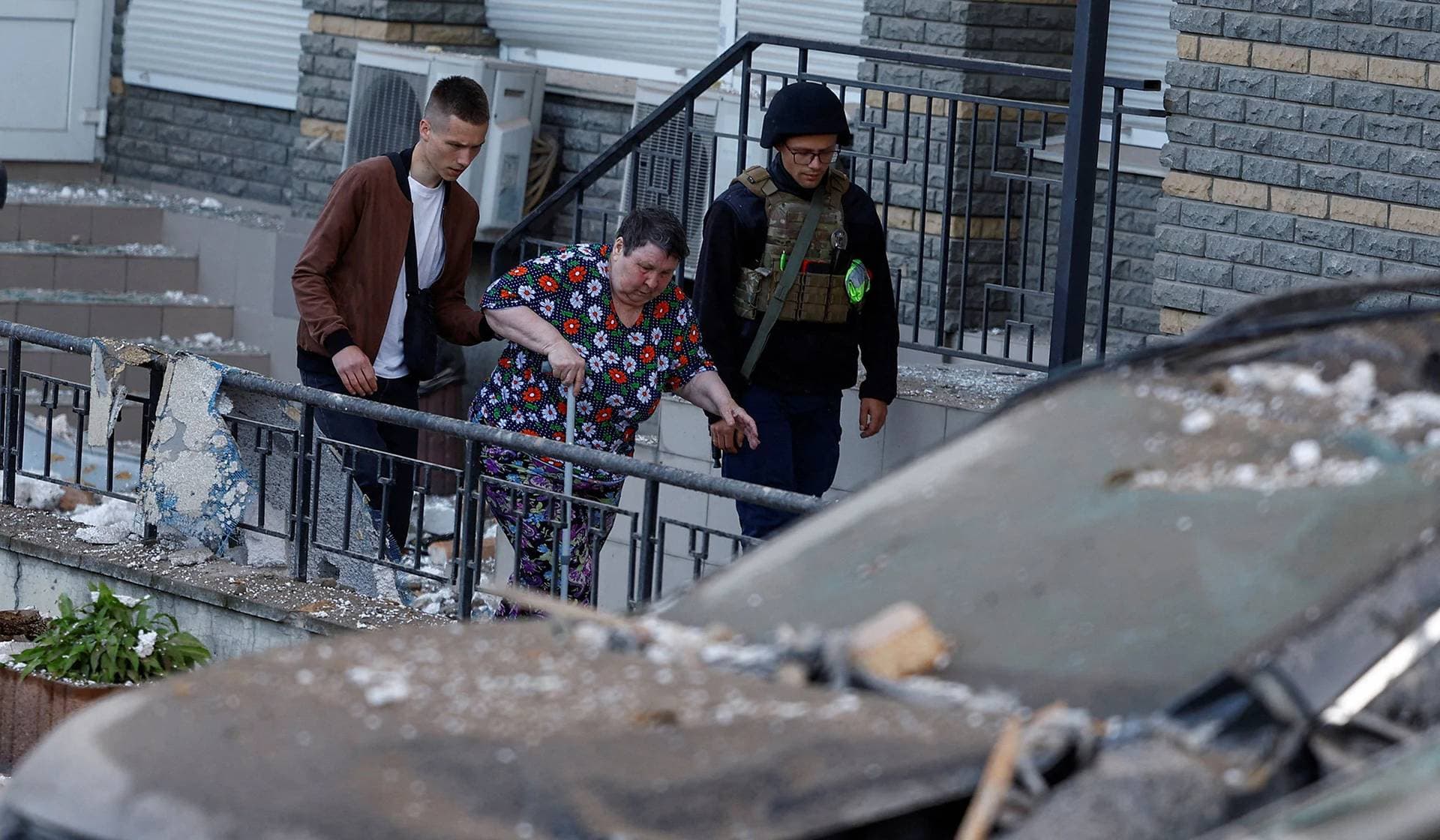 Men help a woman to be evacuated from an apartment building heavily damaged during a massive Russian drone strike in Kyiv