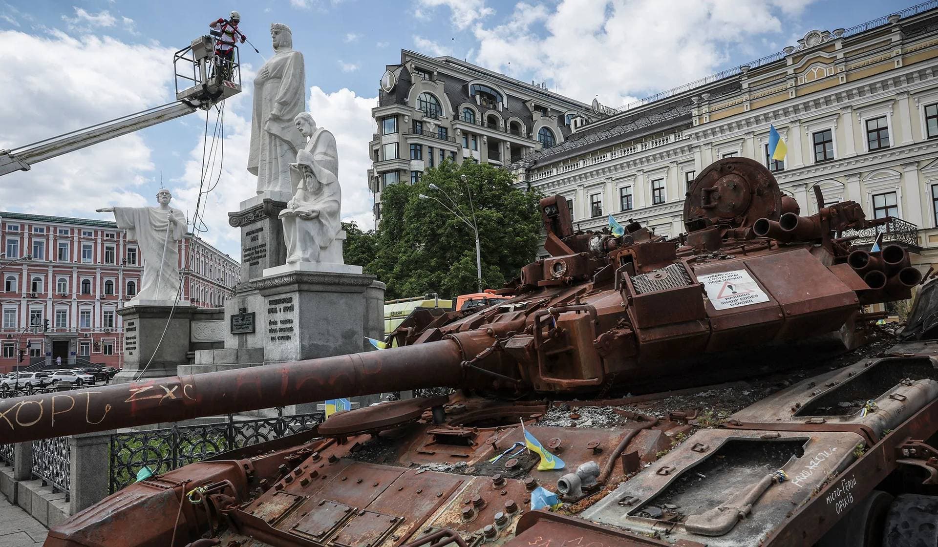 A man cleans up the monuments of Princess Olga, Apostle Andrew, Saints Cyril and Methodius, which were recently uncovered from protective sand bags in Kyiv