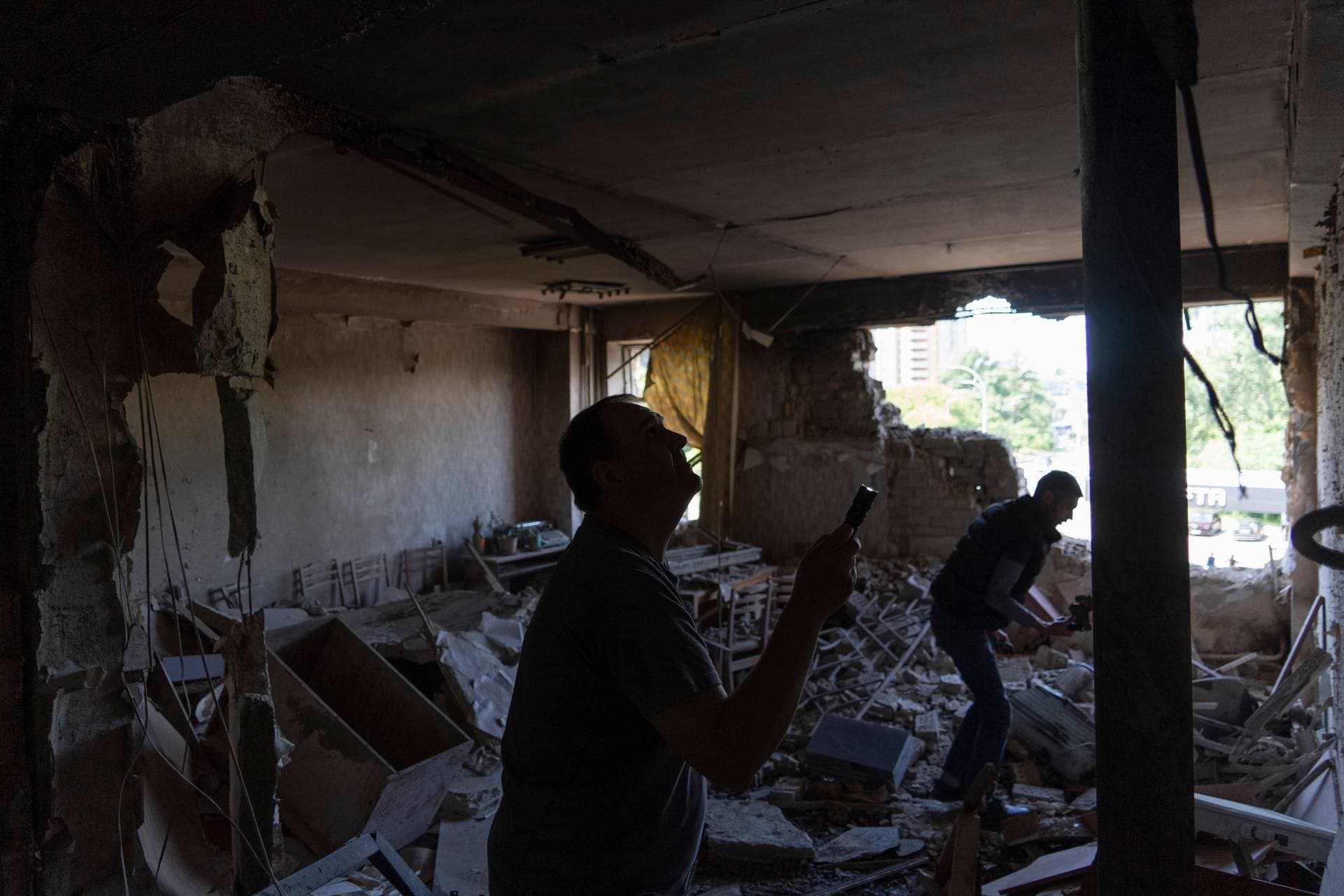 Men inspect their office damaged by a drone during a night attack, in Kyiv