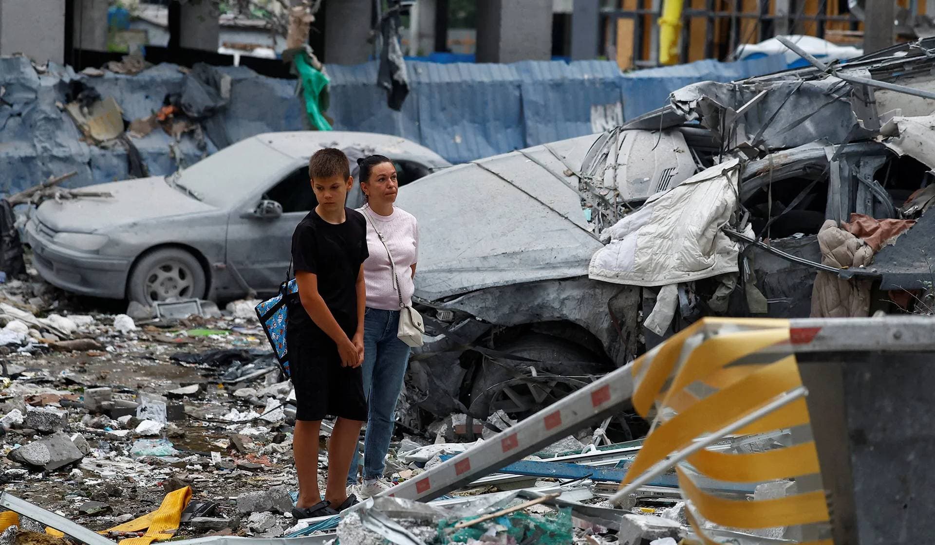 Residents stand amid debris at the site of an apartment building heavily damaged during Russian missile and drone strikes in Kyiv