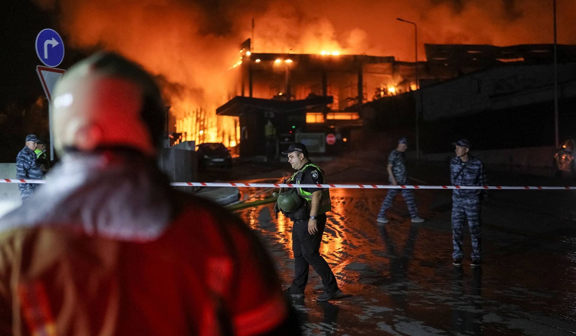 Police officers and security guard at the site of the building of a supermarket warehouse hit by a Russian missile strike in Kyiv