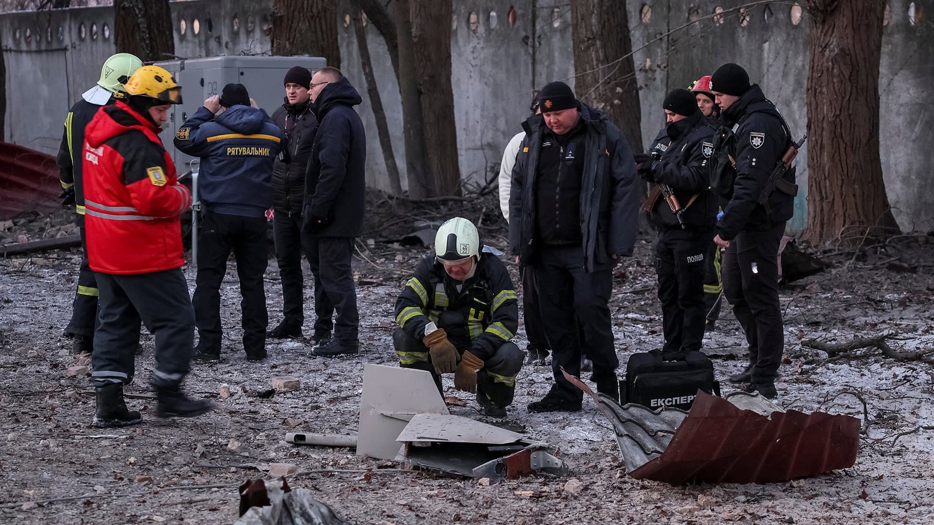 Emergency services and police officers examine parts of a drone at the site of a building destroyed by a Russian drone attack in Kyiv