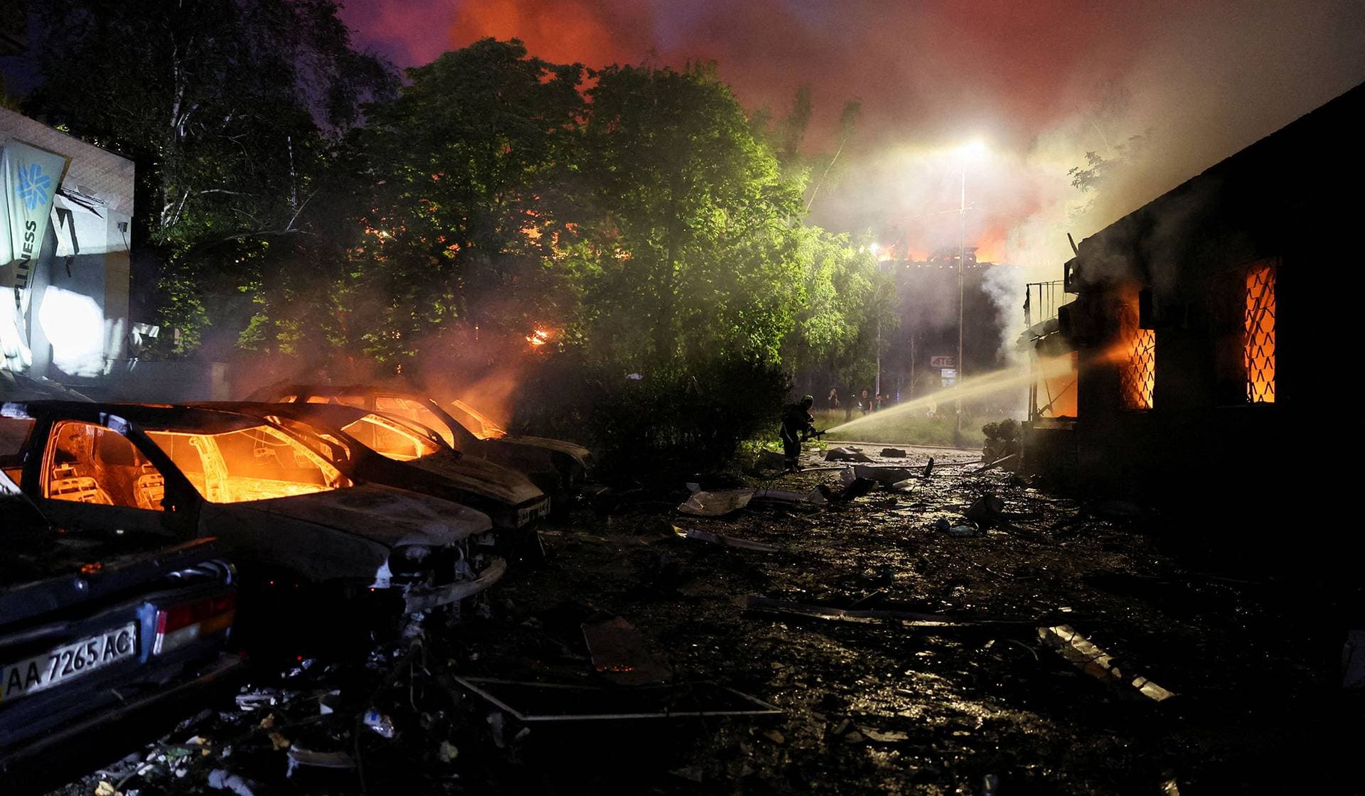 A firefighter works near burning cars at the site of an apartment building damaged during Russian missile strikes in Kyiv