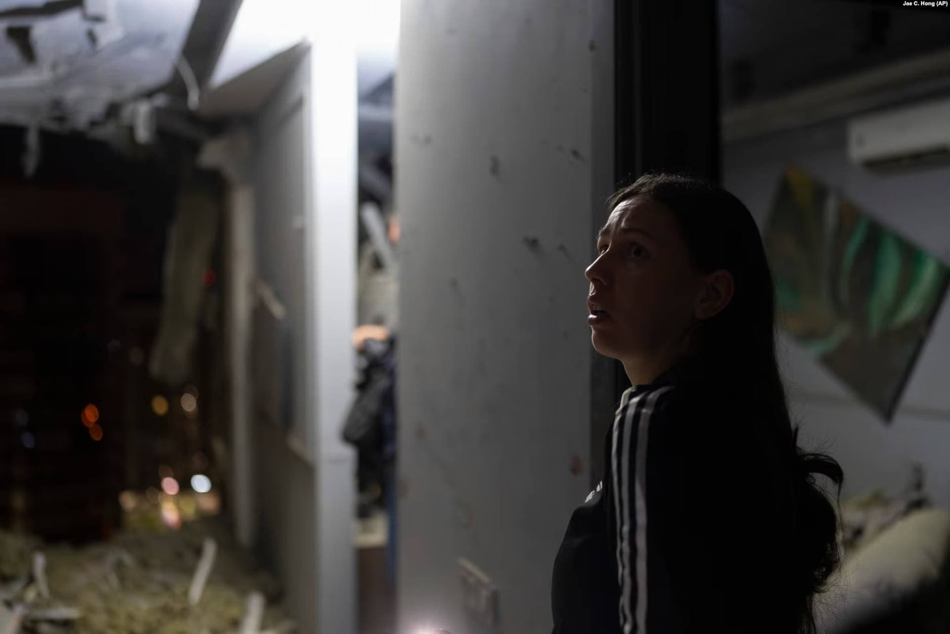 A resident surveys her neighbor's apartment that was damaged during the drone attack