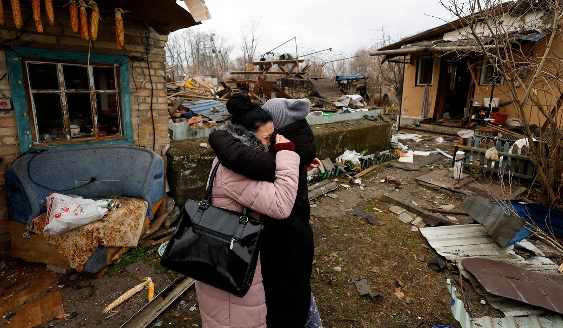 A local resident embraces a friend as she reacts next to her mother's house damaged during a Russian missile strike in Kyiv