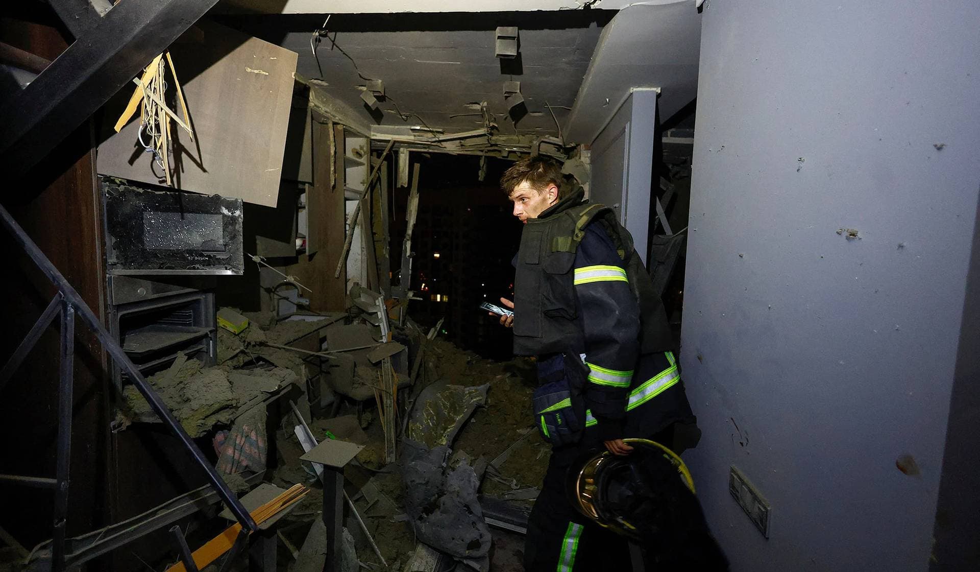 A rescuer inspects an apartment inside a residential building damaged during a Russian drone strike in Kyiv