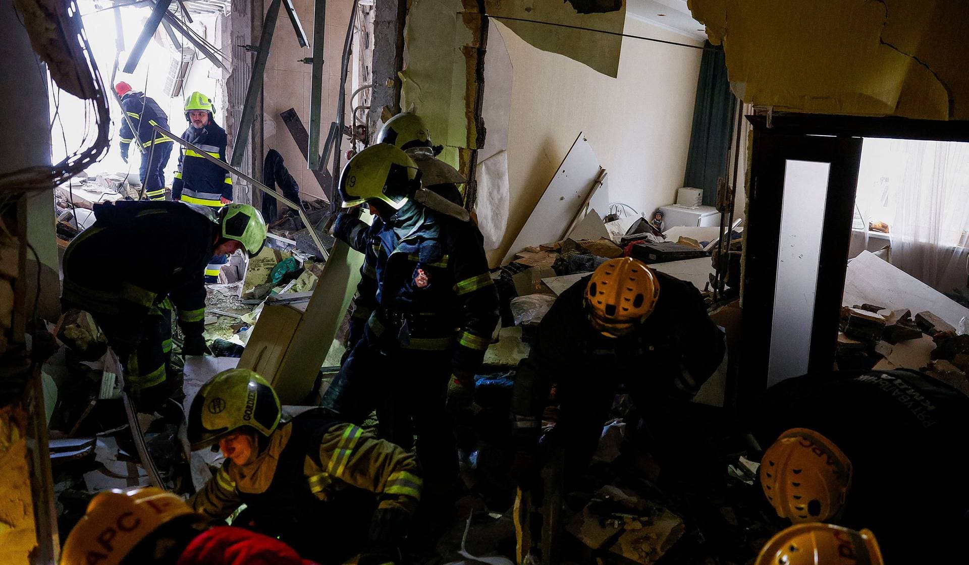 Firefighters work at the site of an apartment building hit during Russian missile and drone strikes in Kyiv
