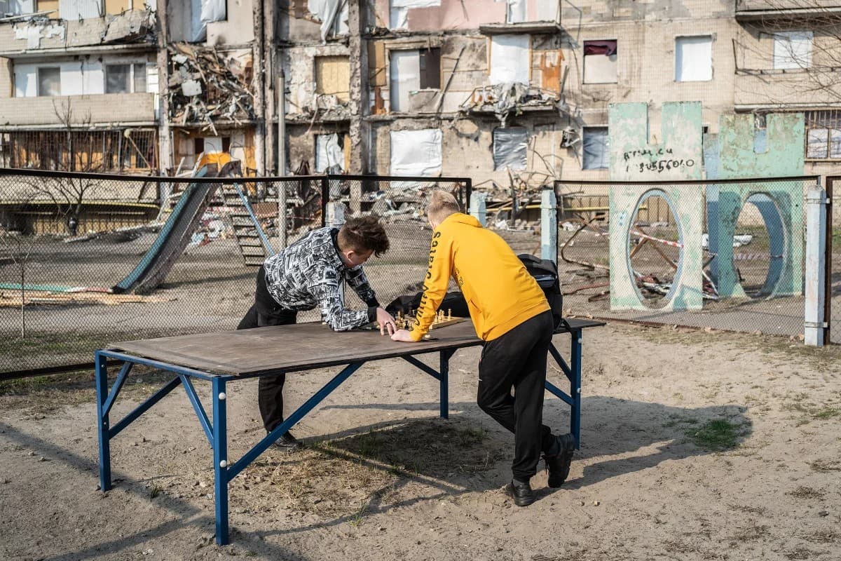 Sasha and Anton, both 15, play chess near a ruined building in Kyiv on March 24.