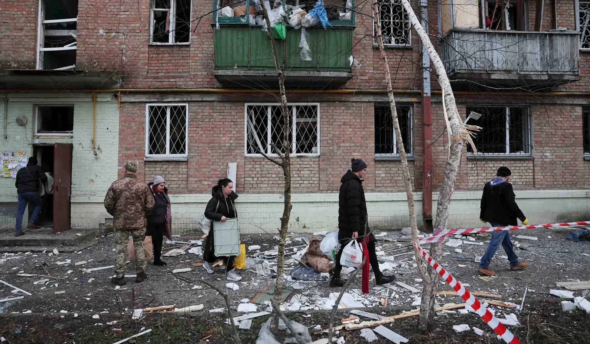 Local residents walk outside a building damaged during a Russian missile strike in Kyiv