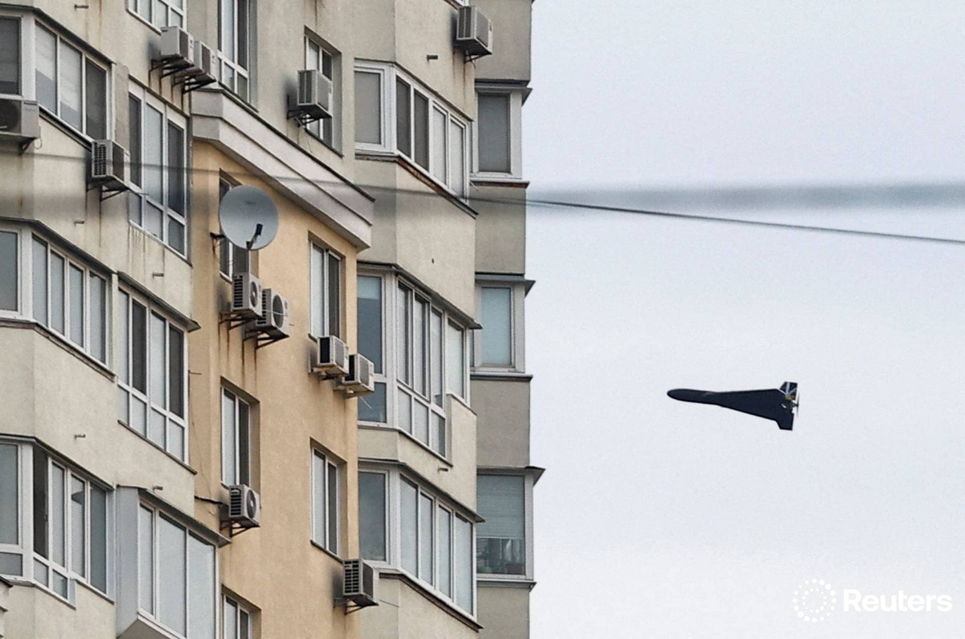 A Russian Geran 2 kamikaze drone flies next to a building in Kyiv