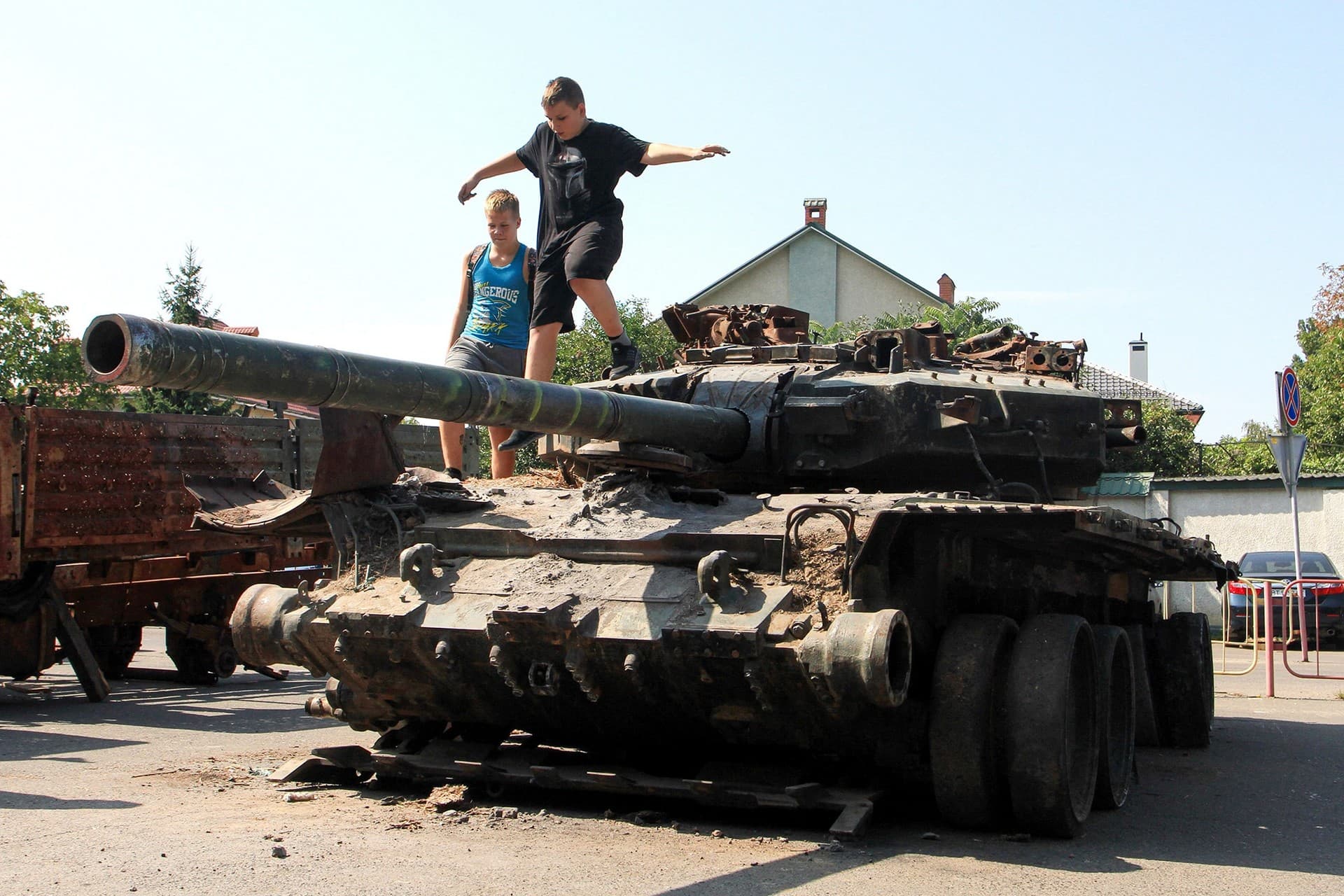 Teenagers play on the turret of a burnt Russian T-90 tank