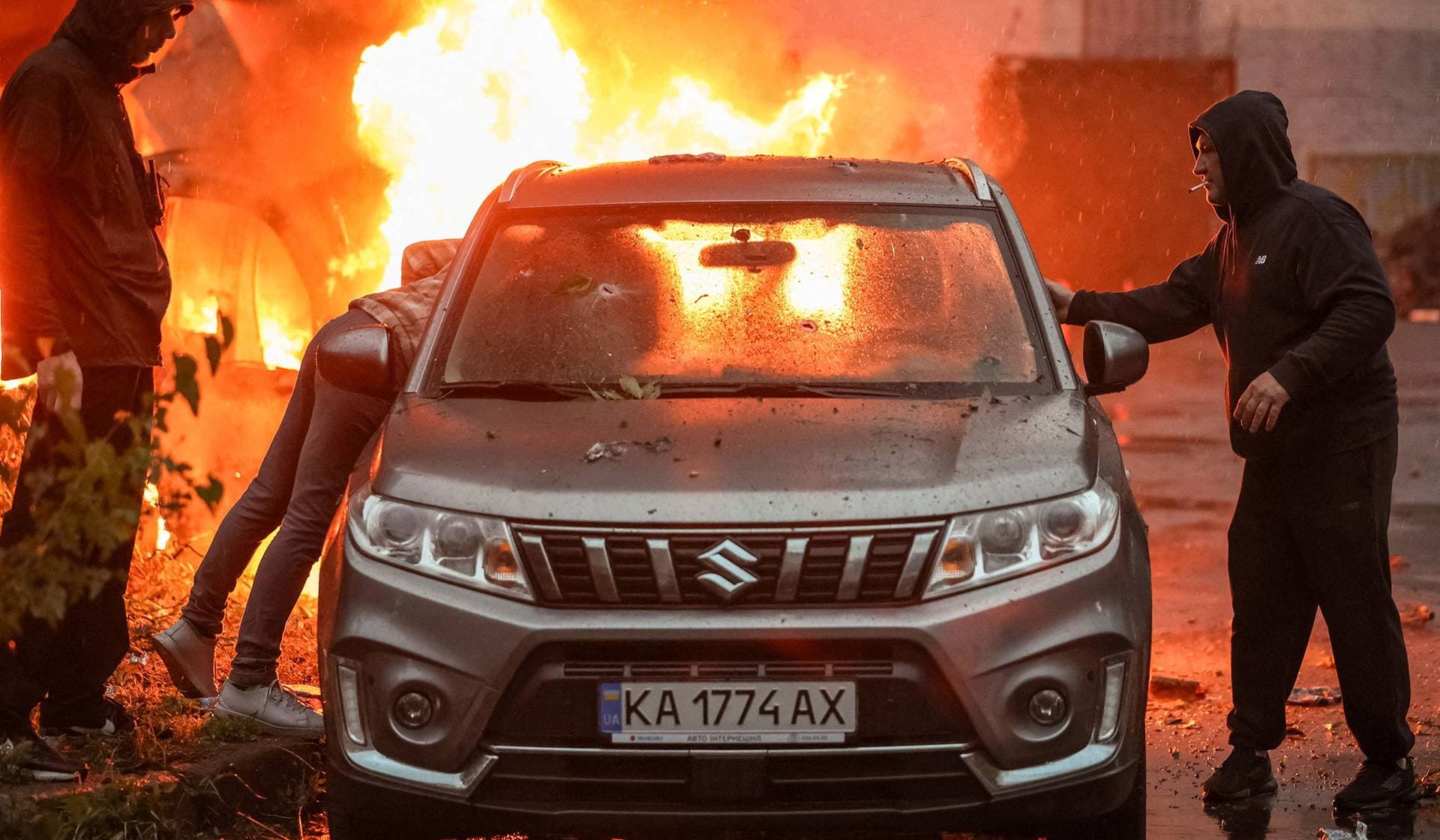 Residents try to move a car from a site of a Russian missile and drone strikes in Kyiv