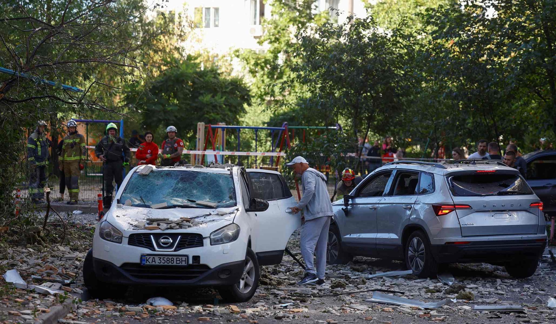 A man inspects his damaged car outside an apartment building hit by a Russian drone strike in Kyiv