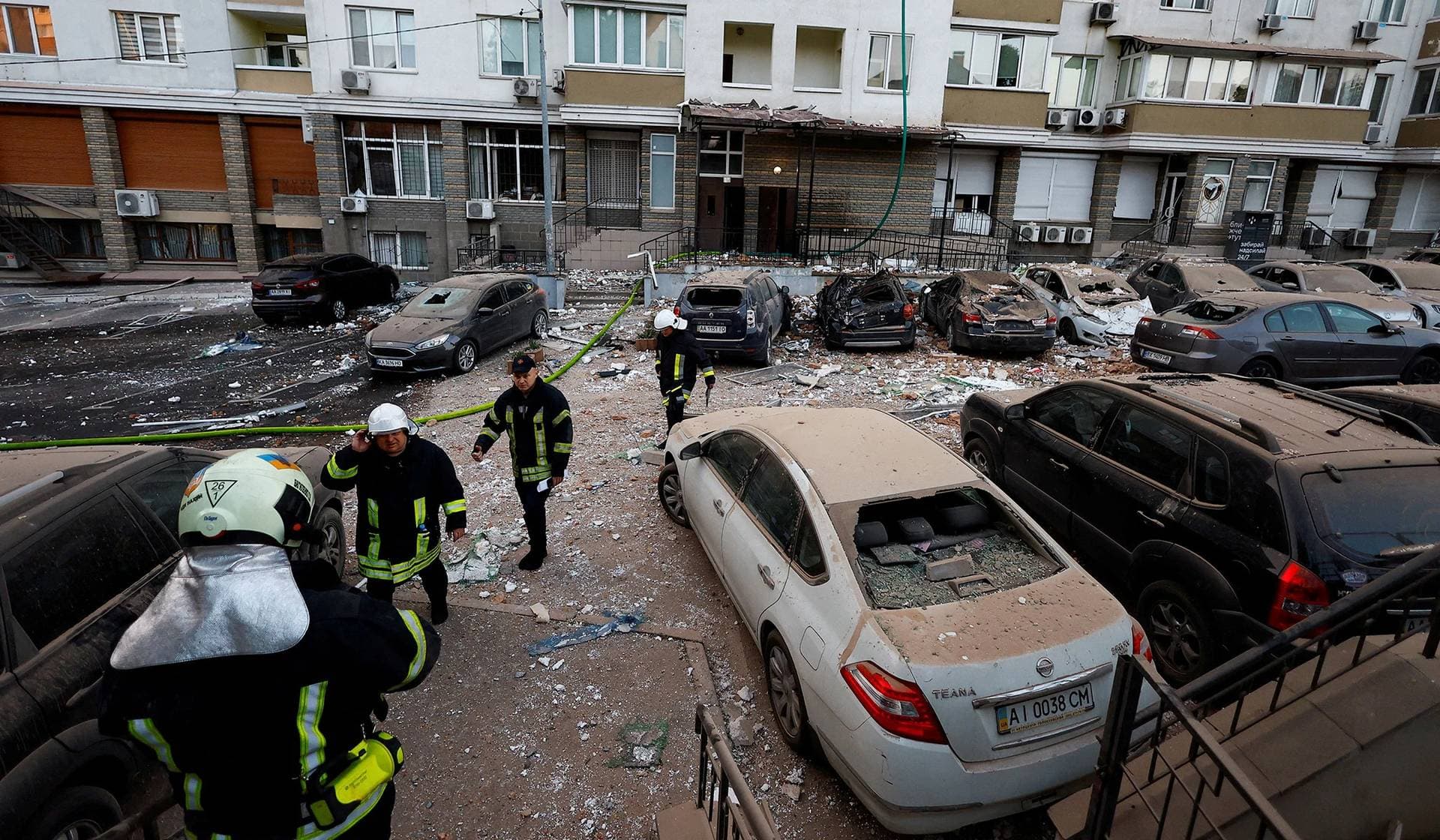 Firefighters work near cars damaged during a massive Russian drone strike in Kyiv