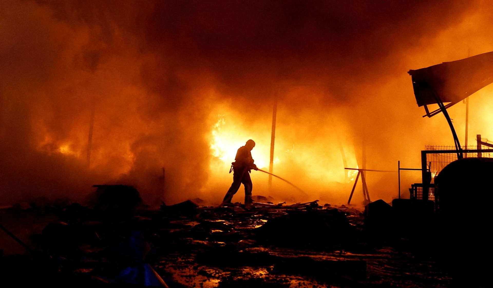 A firefighter battles a blaze at a business hit by Russian missile and drone strikes in Kyiv