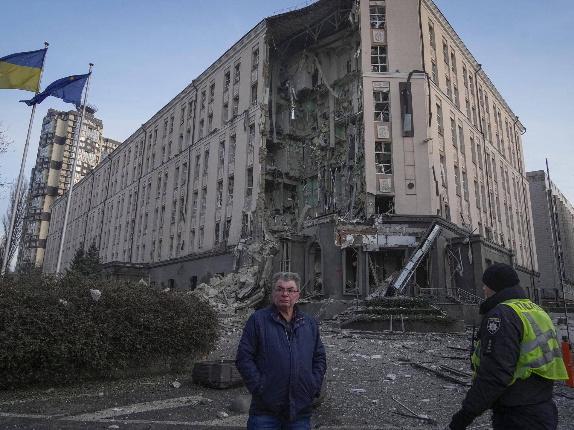 People stand in front of damaged hotel at the scene of Russian shelling in Kyiv