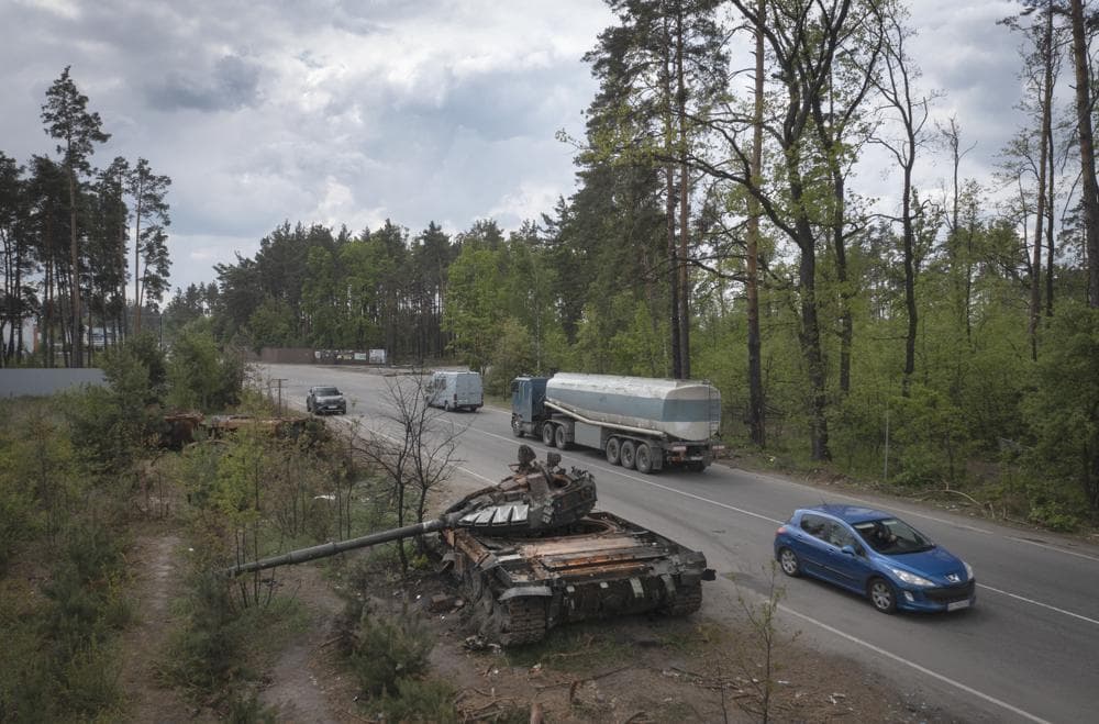 Cars pass by Russian tanks destroyed in a recent battle against Ukrainians in the village of Dmytrivka, close to Kyiv