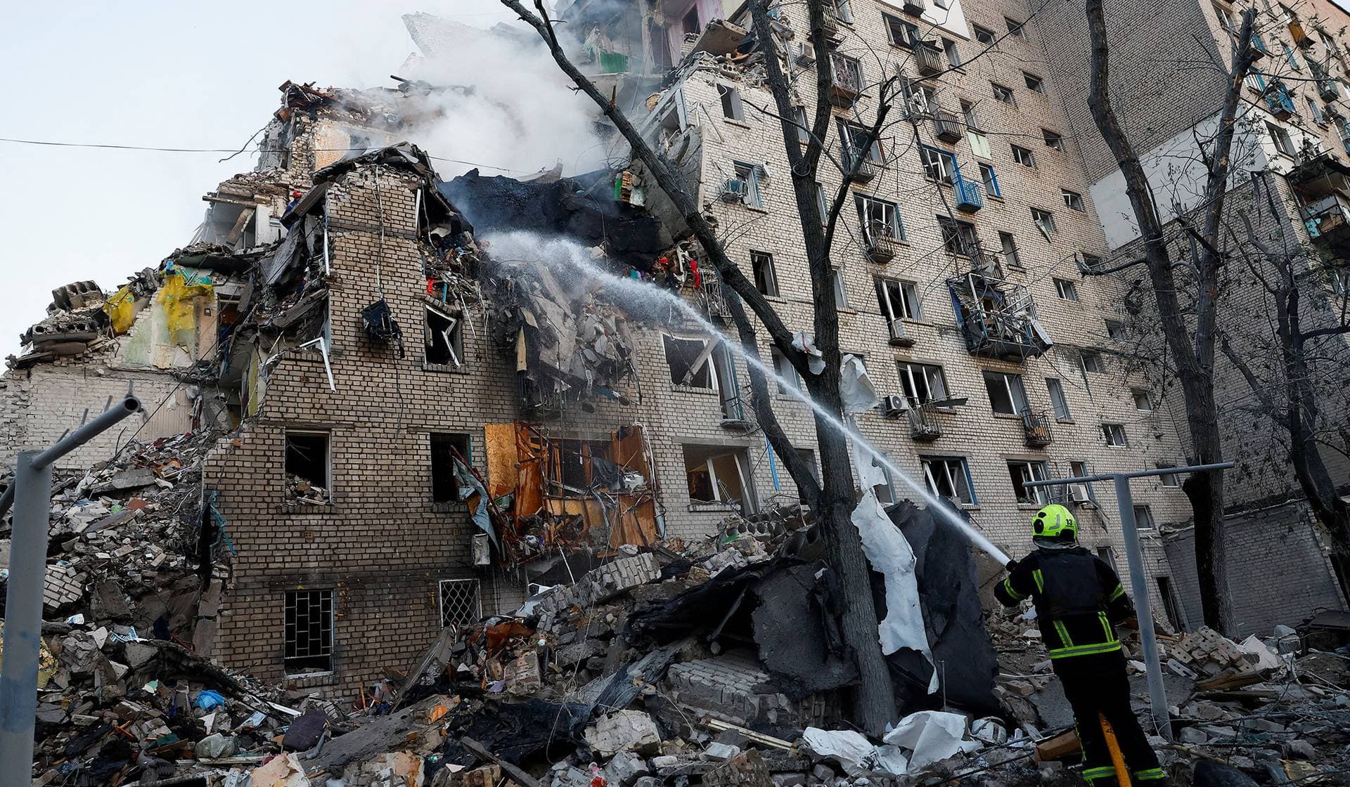 A firefighter works at the site of an apartment building damaged during overnight Russian missile and drone strikes in Kyiv
