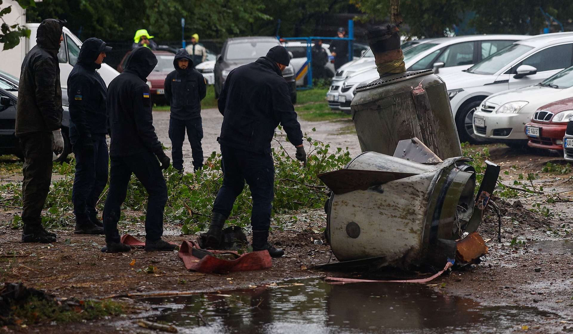 Emergency deminers stand next to parts of a Russian ballistic missile before loading it into a demining truck in Kyiv