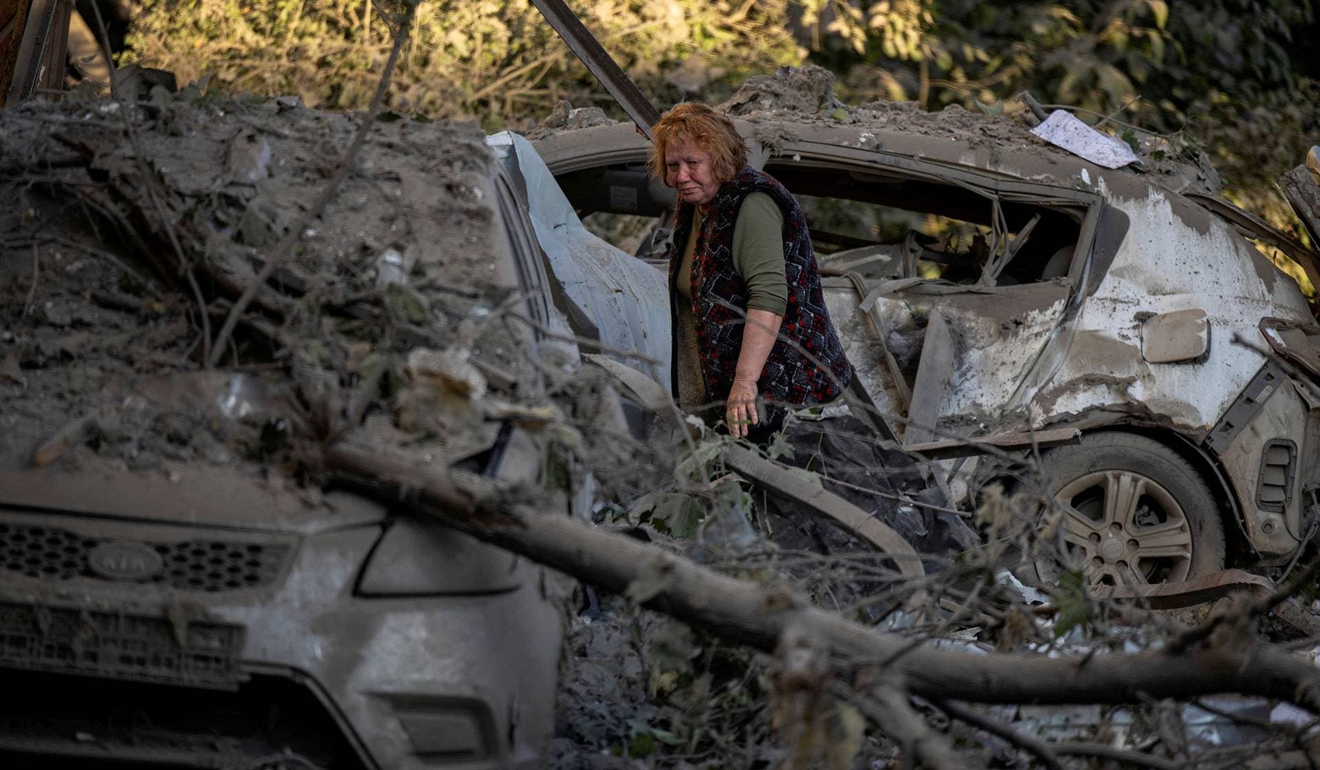 A resident walks amid debris outside her damaged apartment block after a nearby building got struck during overnight Russian missile and drone attacks in Kyiv