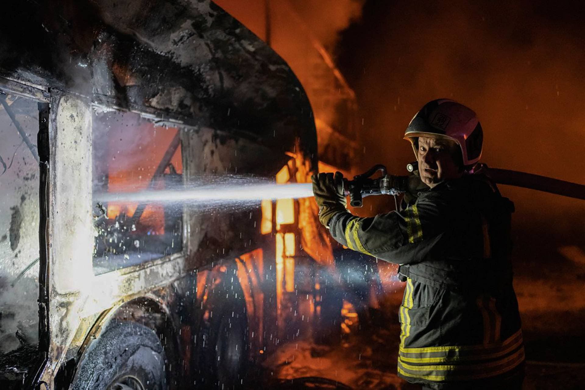 a firefighter tries to put out fire caused by fragments of a Russian rocket after it was shot down by air defense system during the night Russian rocket attack in Kyiv